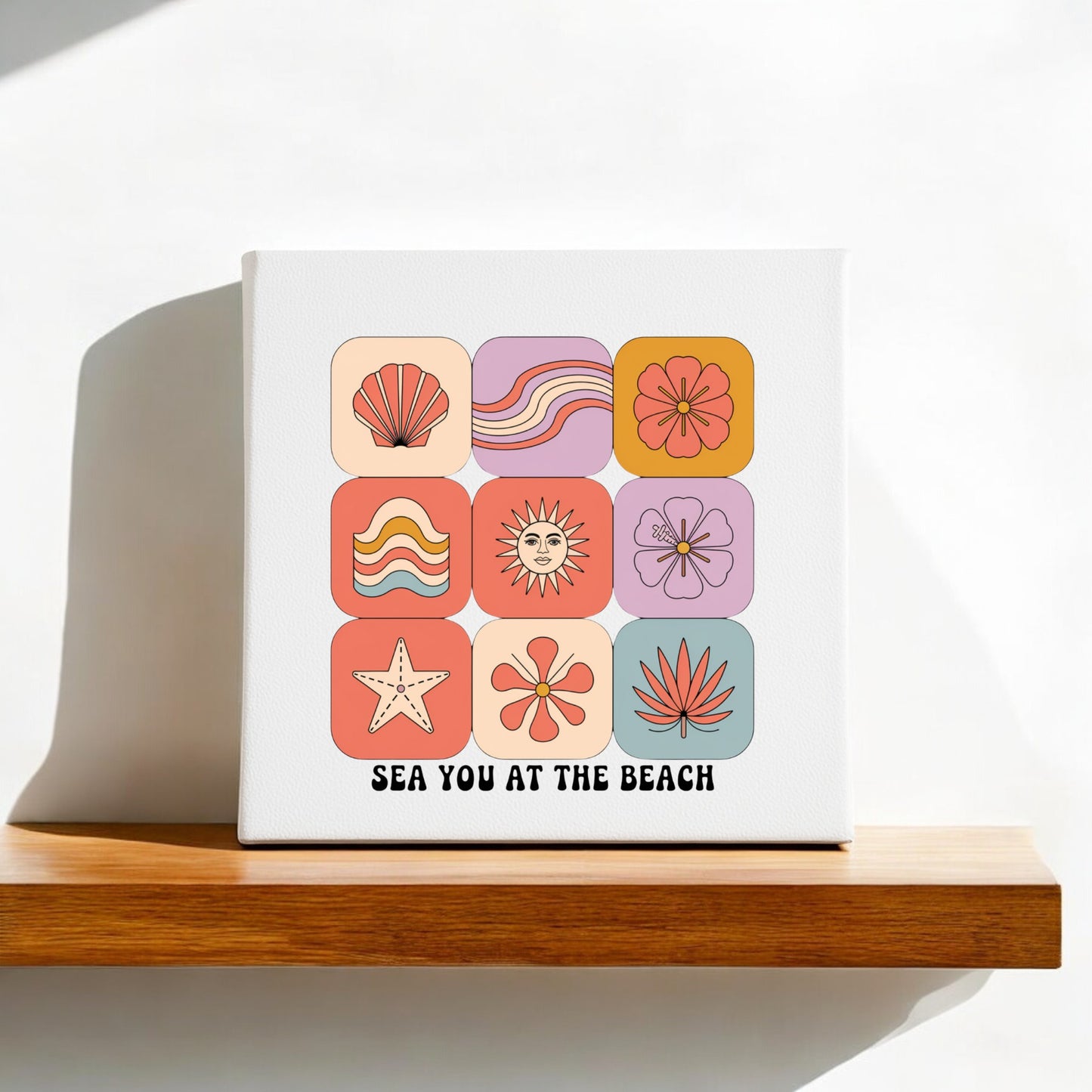 The Sea You at the Beach Canvas – Retro Coastal Wall Art by Mirabilia Boutique features vibrant, retro icons and “SEA YOU AT THE BEACH” text, making a playful coastal accent for your space. Sunlight casts a soft shadow on this cheerful decor piece.