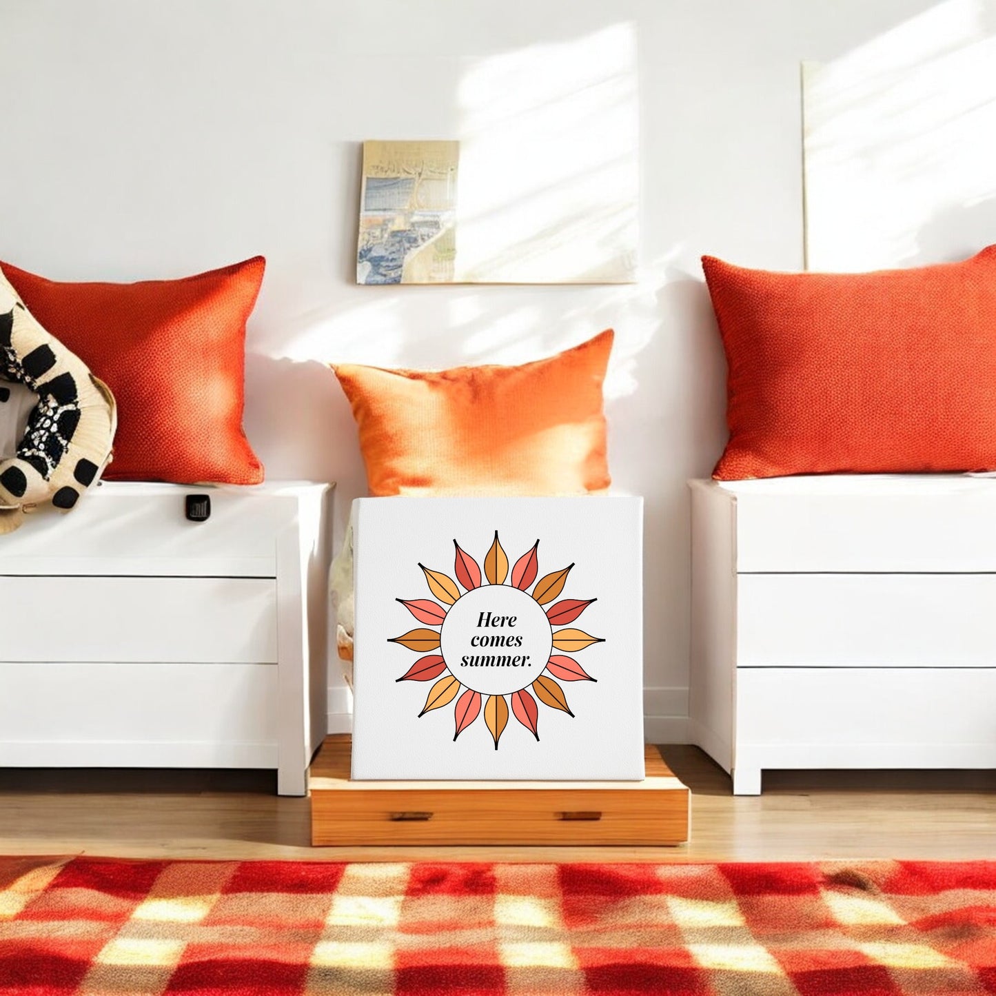 A bright room with two white dressers, orange pillows, and a patterned rug. Between the dressers is Mirabilia Boutique’s "Here Comes Summer Canvas – Retro Sunburst Wall Art." Sunlight streams in from a window.