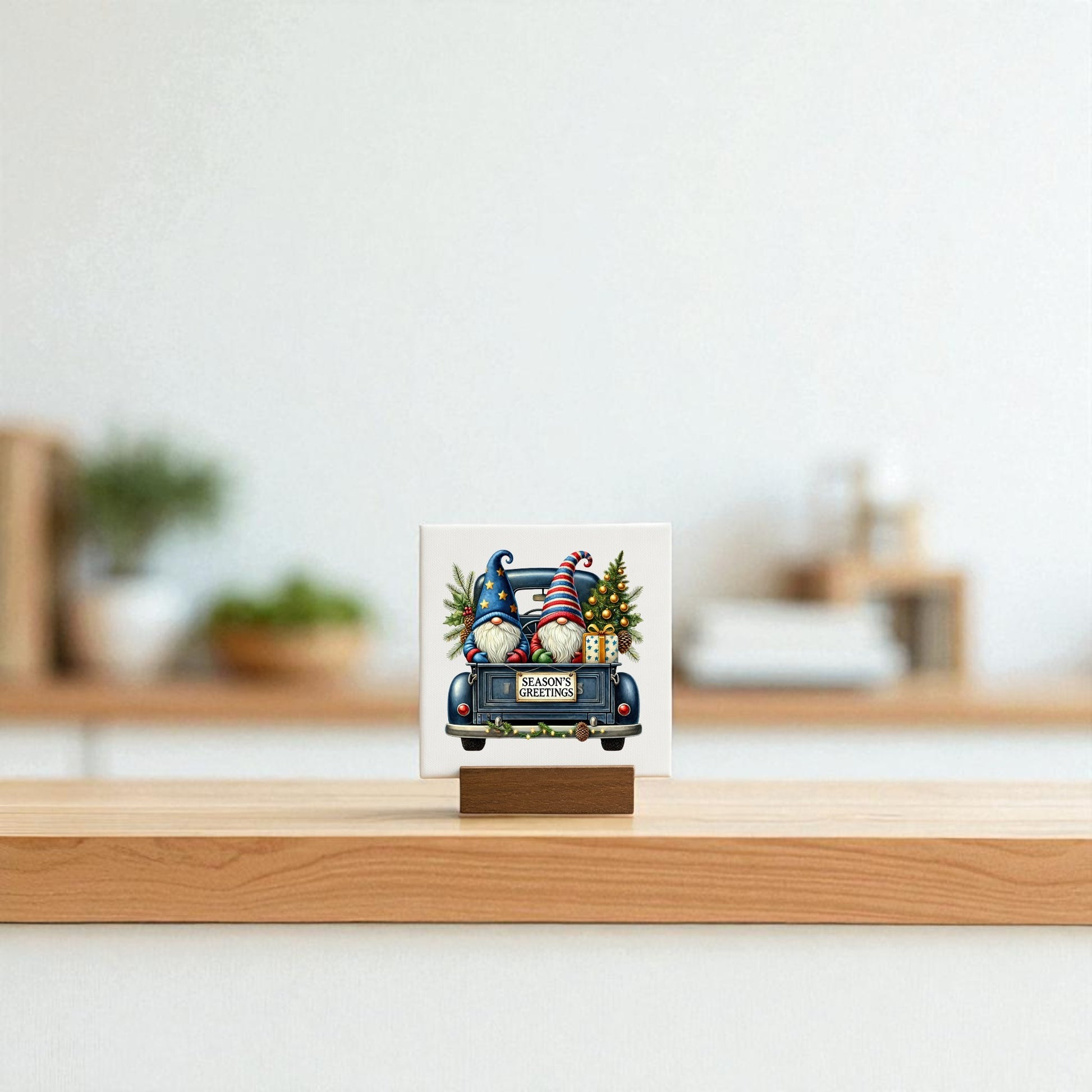 The Mirabilia Boutique Season’s Greetings Gnome Mini Sign, a 4x4 holiday canvas featuring a festive gnome scene and “Merry Christmas” message, sits on a wooden stand atop a light surface with a softly blurred background.