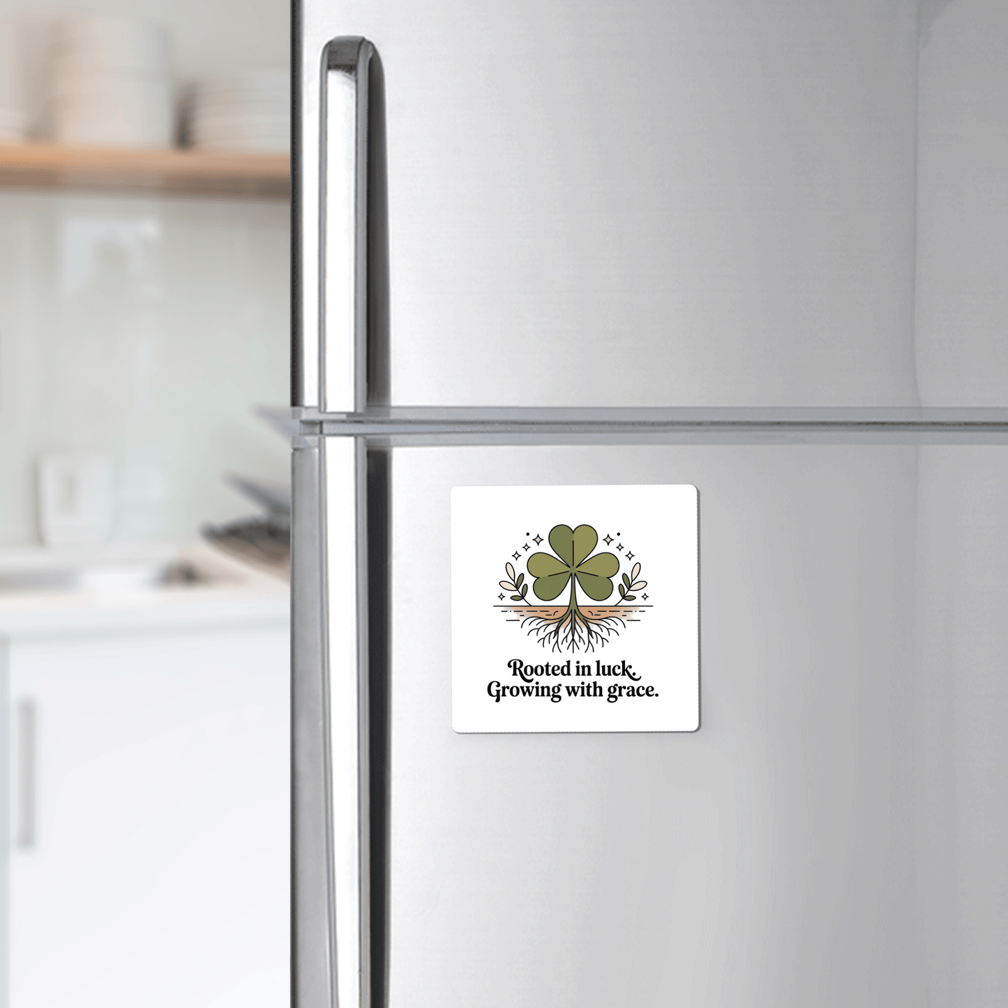 The Rooted in Luck Shamrock Magnet by Mirabilia Boutique, featuring a four-leaf clover with roots and the phrase "Rooted in luck, Growing with grace," is displayed on a stainless steel fridge in a cozy kitchen.