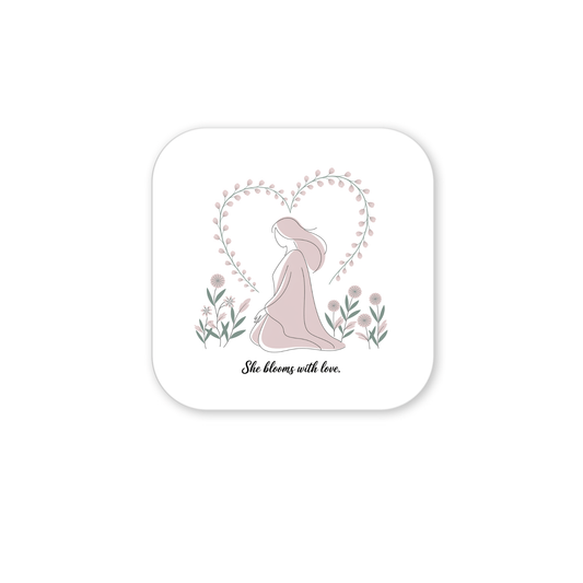 The She Blooms with Love Magnet by Mirabilia Boutique features a minimalist woman in a flowing dress amid flowers, a heart-shaped vine behind her, and the text "She Blooms with Love"—a meaningful décor and gentle floral mom gift.