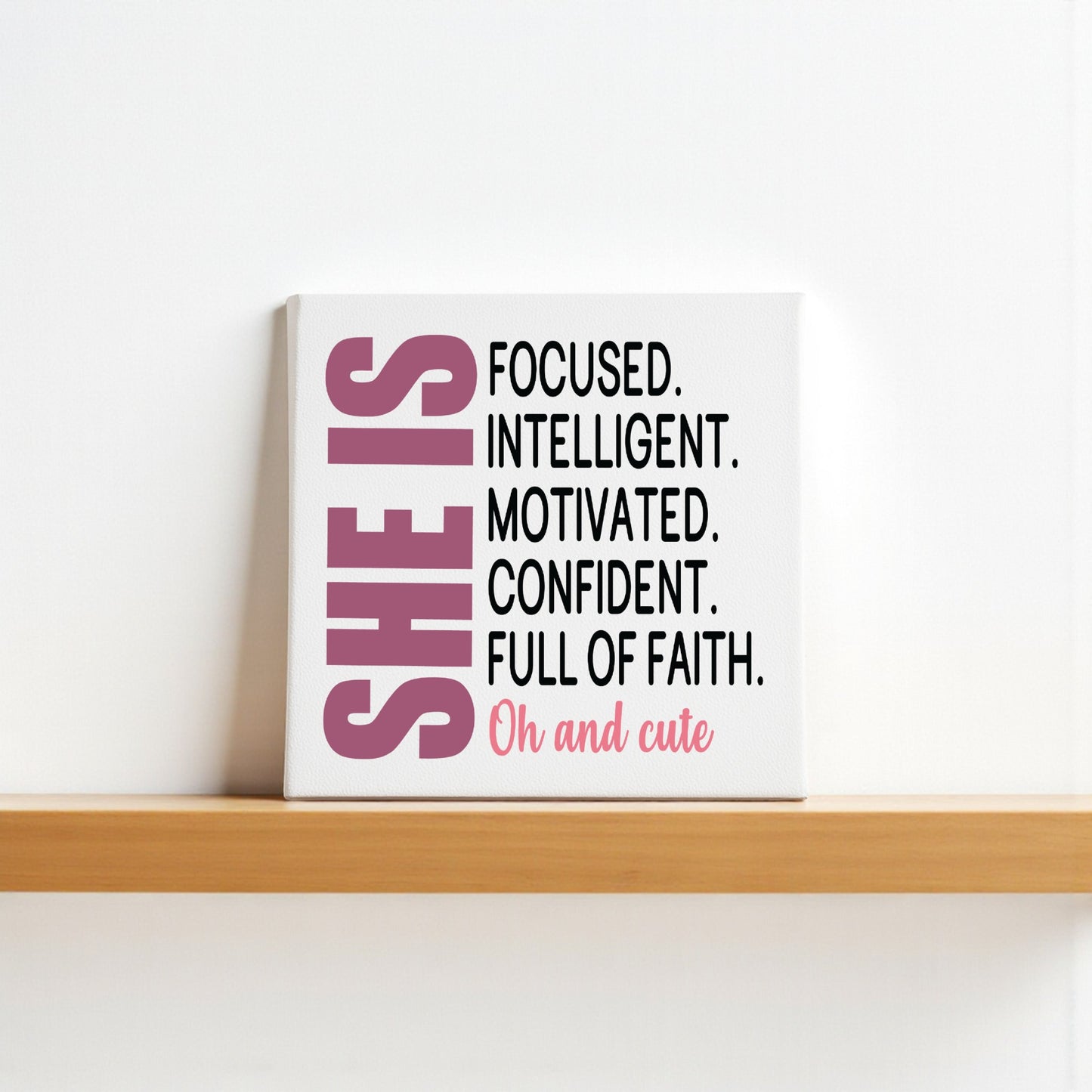 The She Is Focused Motivated Confident Canvas by Mirabilia Boutique features empowering affirmations and bold pink "SHE IS" text, making this 8x8 inspirational wall art a truly uplifting décor piece.