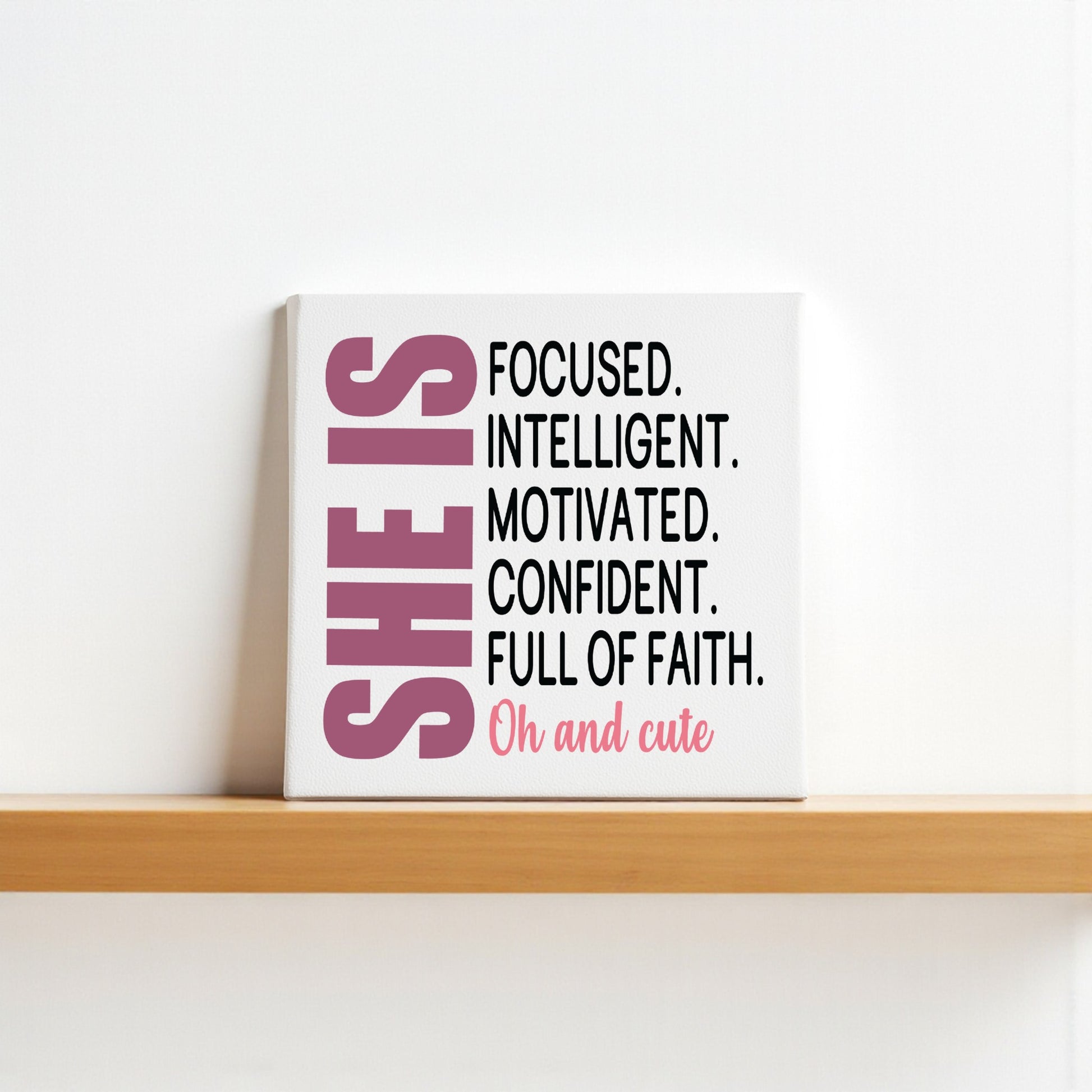 The She Is Focused Motivated Confident Canvas by Mirabilia Boutique features empowering affirmations and bold pink "SHE IS" text, making this 8x8 inspirational wall art a truly uplifting décor piece.