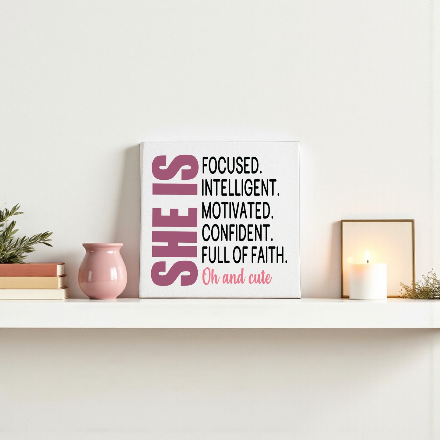 On a white shelf, the Mirabilia Boutique “She Is Focused Motivated Confident” 8x8 canvas inspires with bold affirmations. A pink vase, white candle, and small plant complete this perfect motivational wall art.