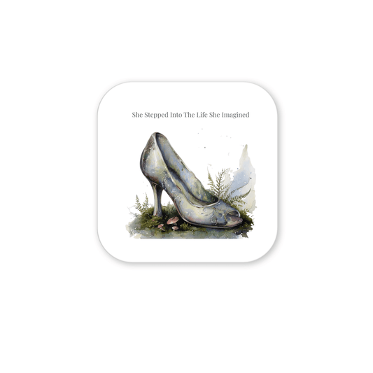 A watercolor glass slipper rests amid grass, moss, and nearby ferns, setting a fairytale scene. Above it, the words "She Stepped Into the Life She Imagined" add inspiration to this Mirabilia Boutique creation. The She Stepped Into the Life She Imagined Magnet is a truly uplifting refrigerator magnet for dreamers and believers alike.