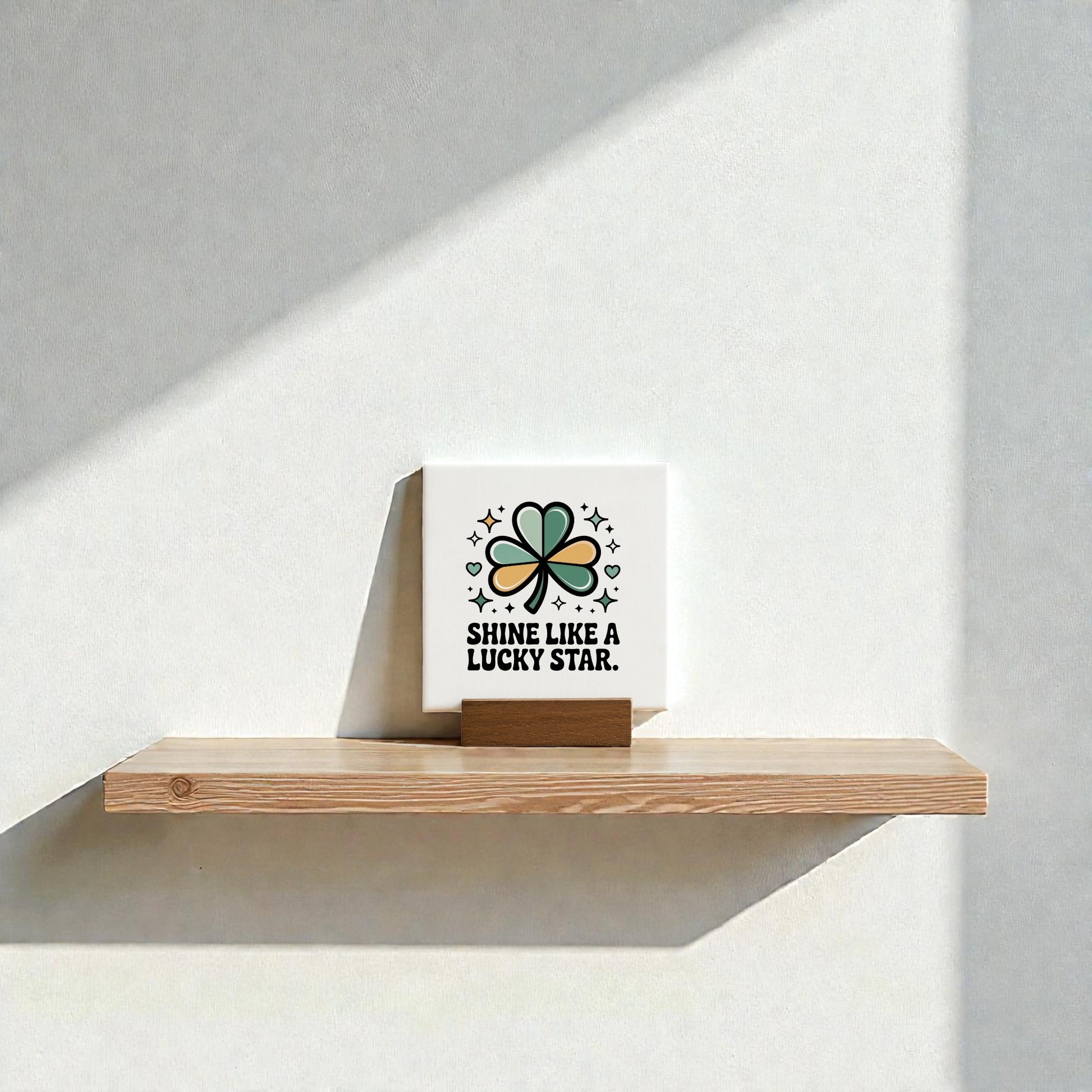 The Mirabilia Boutique Shine Like a Lucky Star Canvas Sign (4x4) features a four-leaf clover and stars, making it perfect St. Patrick’s Day decor. Sunlight casts playful shadows on the wall for added charm.