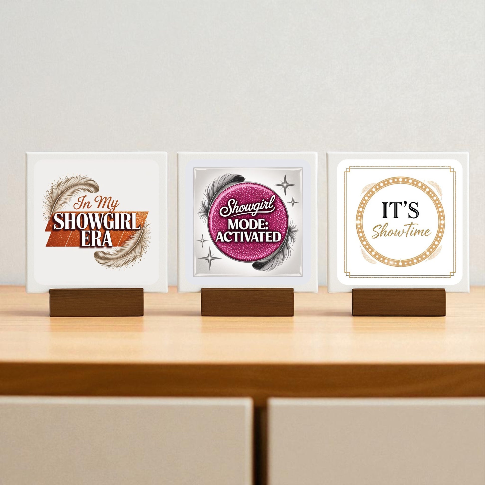 The Showgirl Mini Sign Trio by Mirabilia Boutique features three glam square signs—"In My Showgirl Era," "Showgirl Mode: Activated," and "IT'S Showtime"—with feather or sequin details. Perfect as gift or chic decor for desk and shelves.