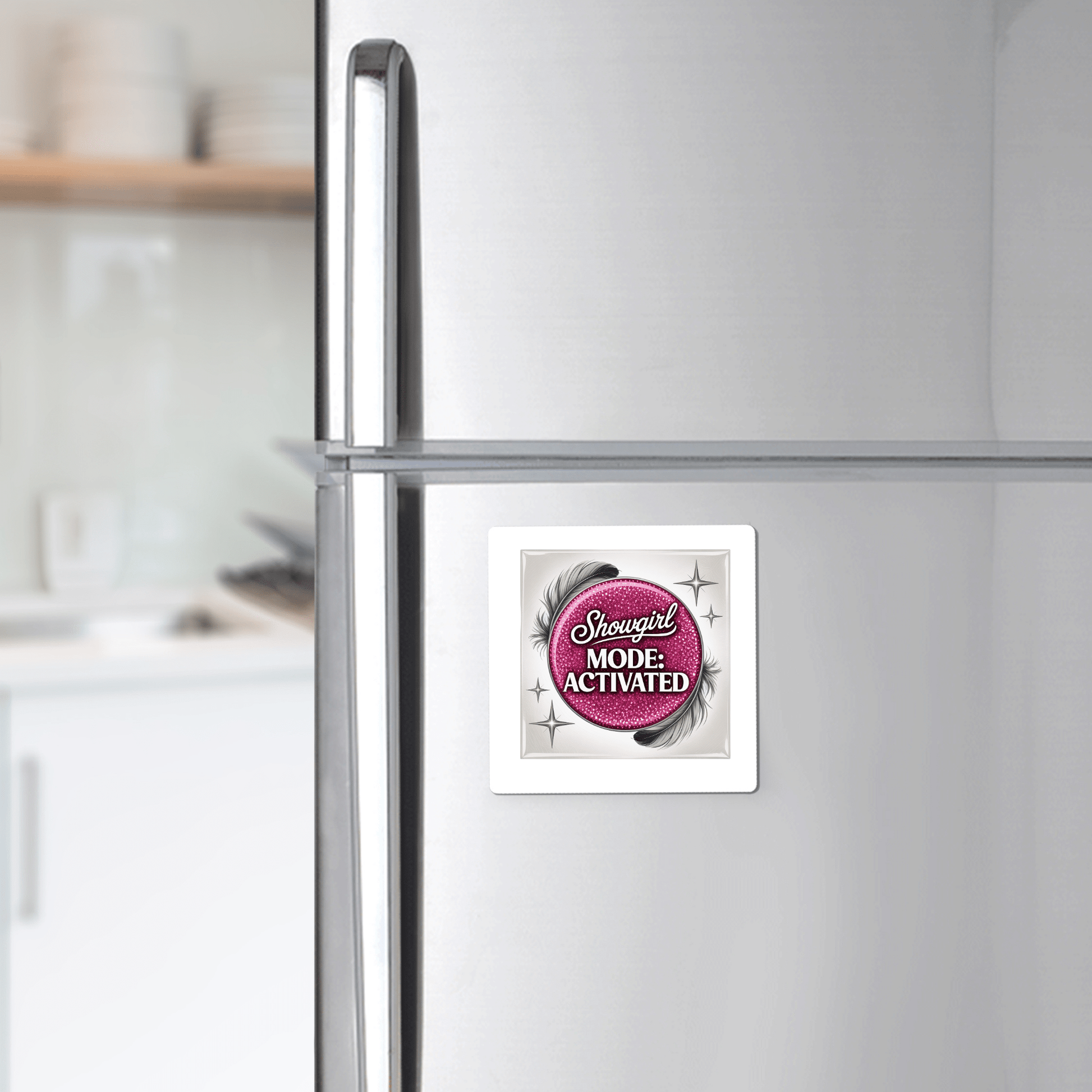 A silver refrigerator in the kitchen displays the Mirabilia Boutique "Showgirl Mode Activated Magnet"—a glam pink fridge decor with a glittery background, black feathers, and sparkling "Showgirl MODE: ACTIVATED" text.