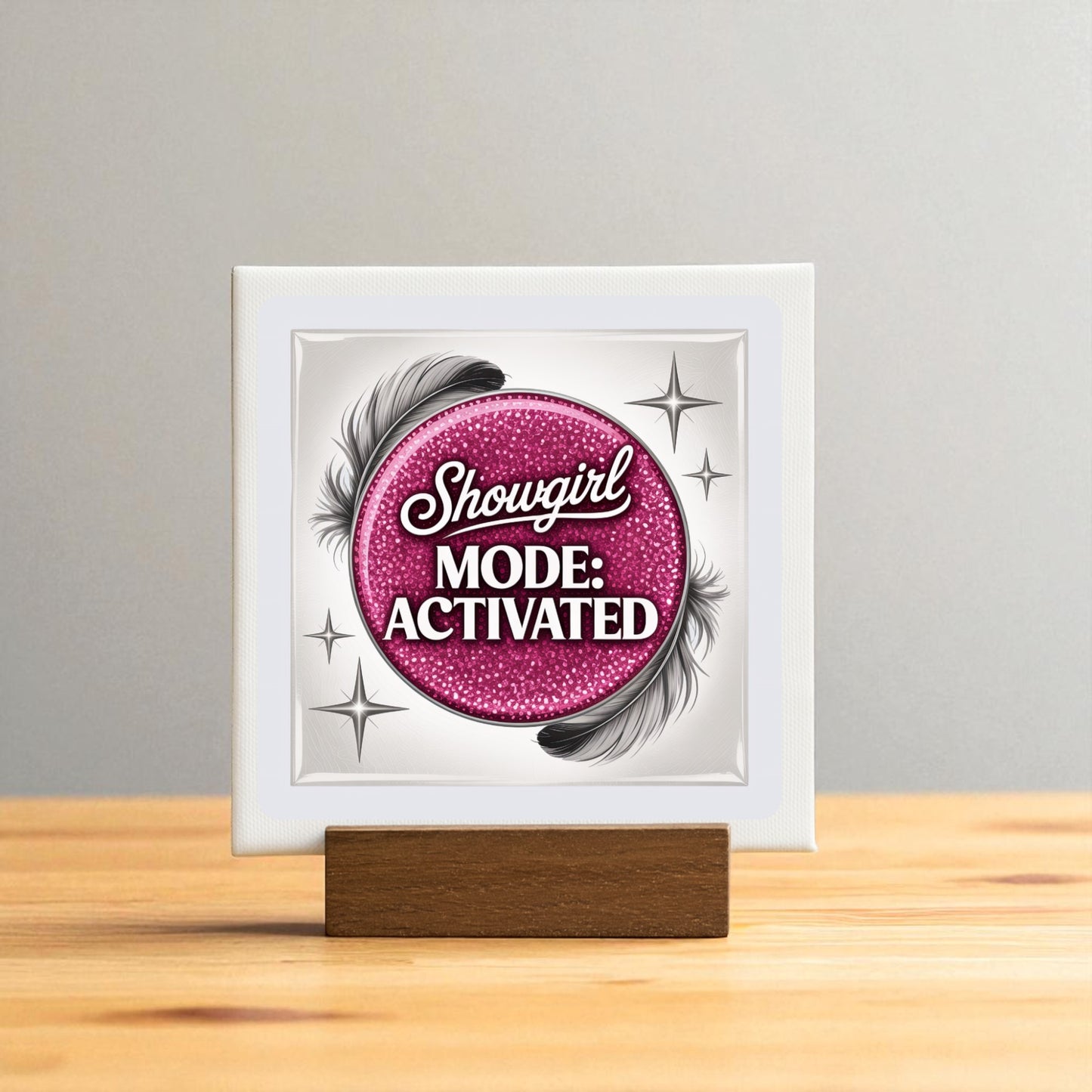 The Showgirl Mode Activated Mini Sign by Mirabilia Boutique features a pink glittery circle, black feathers, and silver stars on a wooden stand—a perfect glam table decor accent for any space.