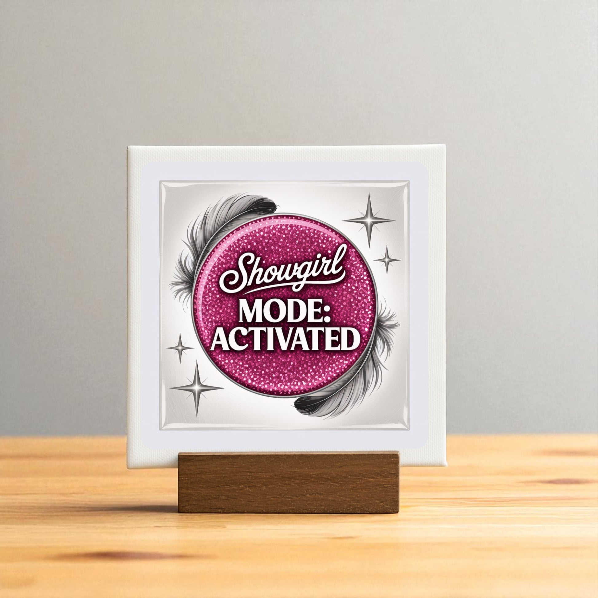 The Showgirl Mode Activated Mini Sign by Mirabilia Boutique features a pink glittery circle, black feathers, and silver stars on a wooden stand—a perfect glam table decor accent for any space.