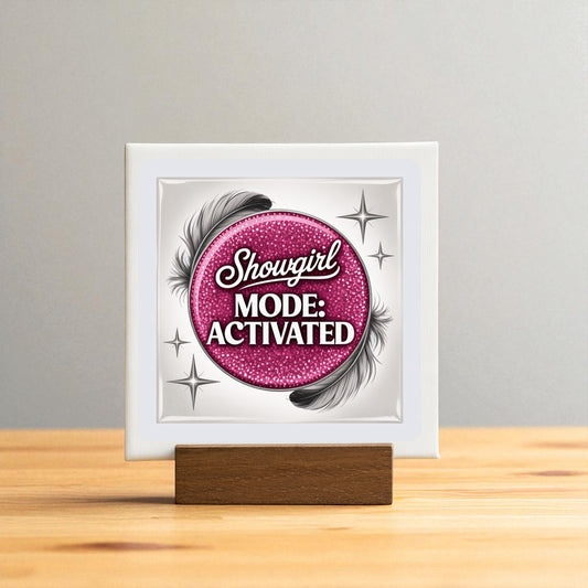 The Showgirl Mode Activated Mini Sign by Mirabilia Boutique features a pink glittery circle, black feathers, and silver stars on a wooden stand—a perfect glam table decor accent for any space.