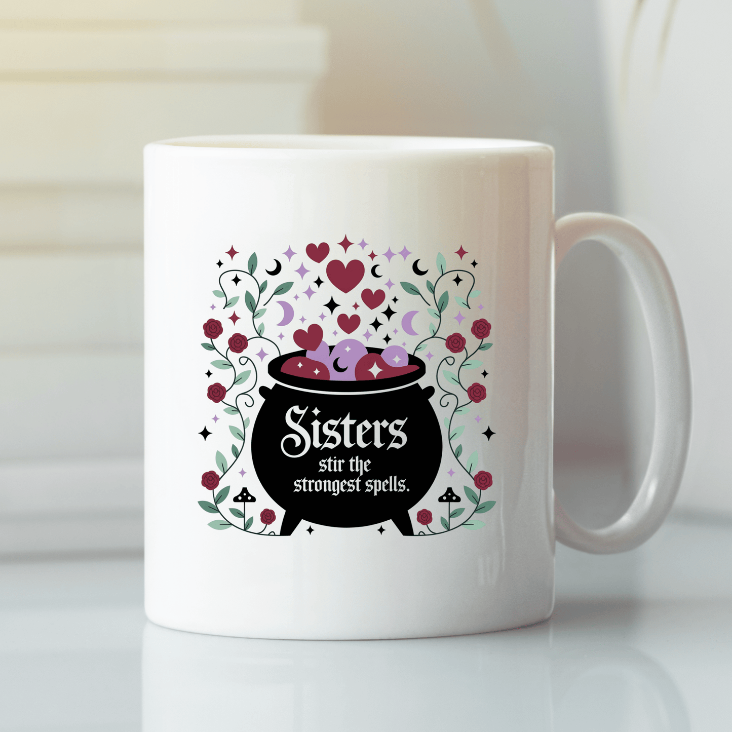 The Sisters Stir the Strongest Spells Mug by Mirabilia Boutique features a black cauldron with hearts, sparkles, and floral accents. Perfect witchy sister gift, its cauldron reads: "Sisters stir the strongest spells.