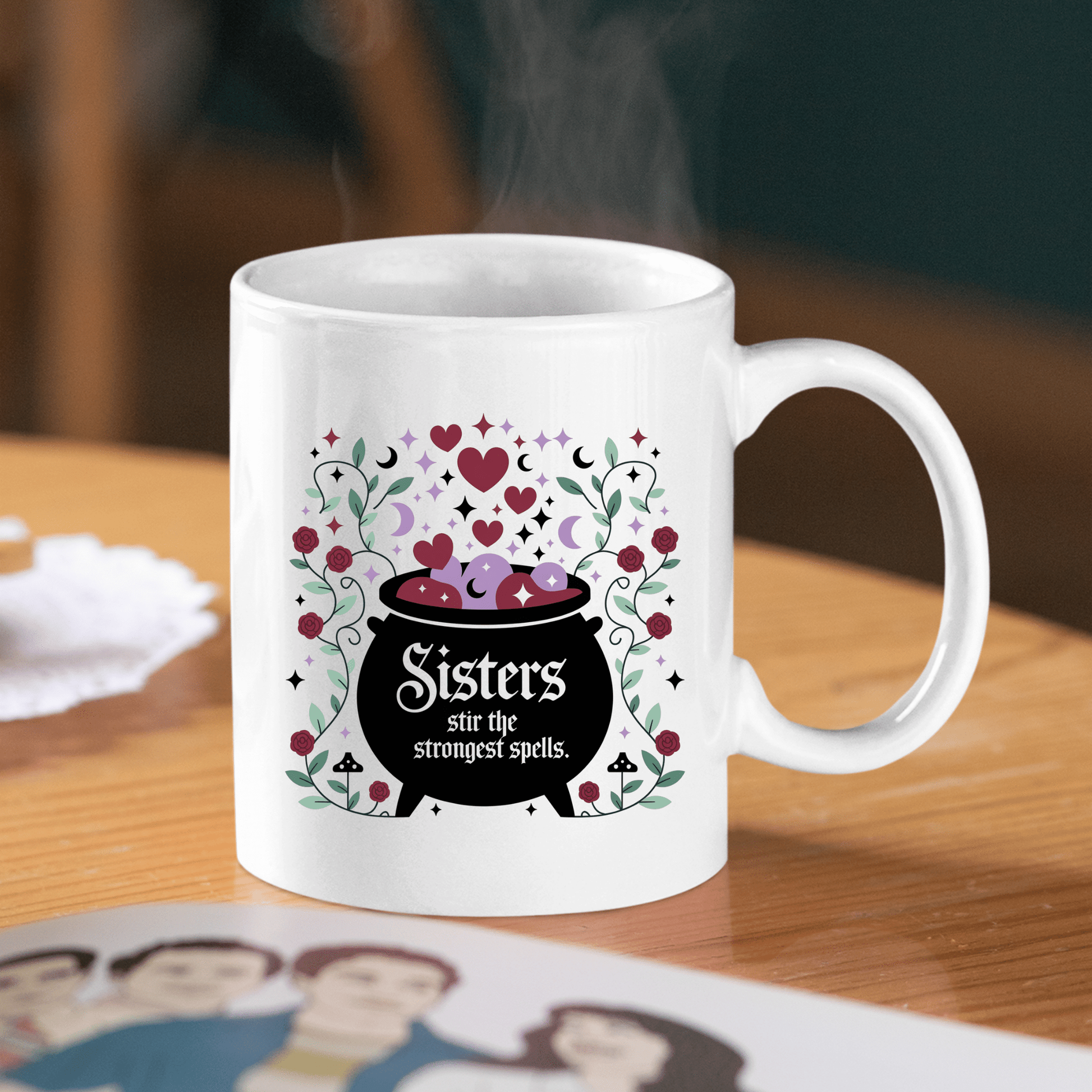 The Sisters Stir the Strongest Spells Mug by Mirabilia Boutique features a cauldron with hearts and flowers and the phrase “Sisters stir the strongest spells”—a perfect witchy sister gift.