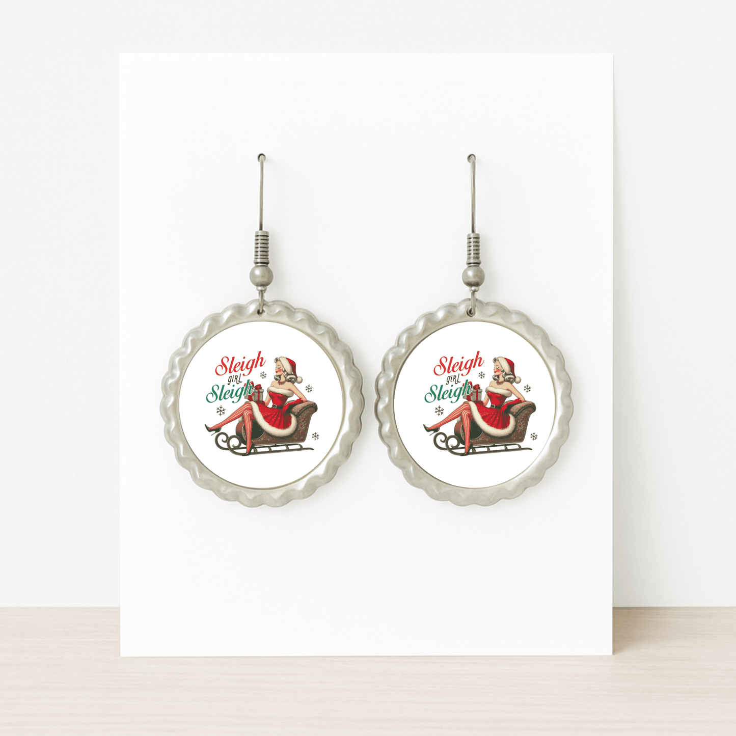 Mirabilia Boutique’s Sleigh Girl Sleigh Earrings feature a vintage Santa-hat woman on a sleigh with “Sleigh Sleigh Sleigh” in festive colors—a retro Christmas jewelry piece perfect for the holiday season.