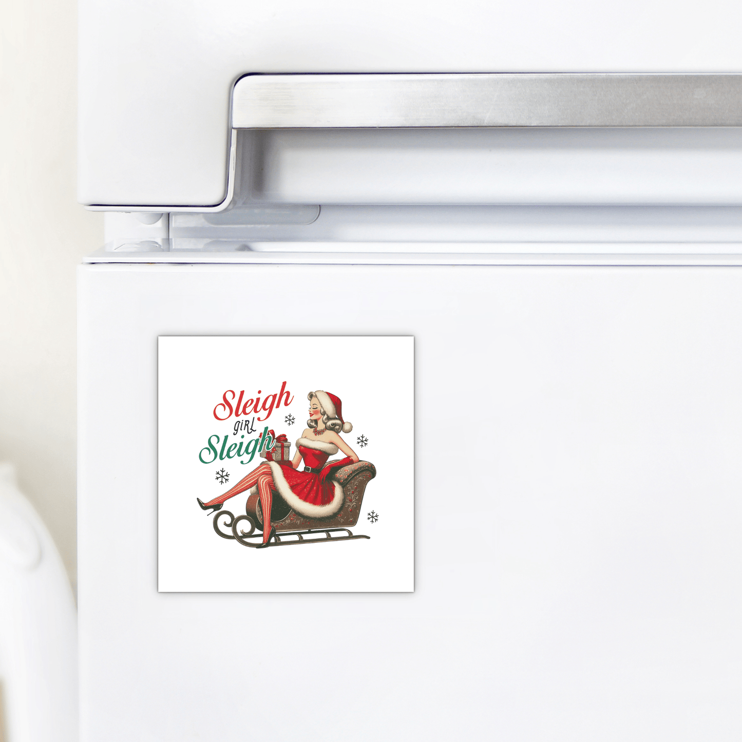 Add vintage flair to your kitchen with the Sleigh Girl Sleigh Magnet from Mirabilia Boutique—a retro holiday fridge magnet featuring a pin-up woman in a Santa outfit, gifts, and festive "Sleigh girl Sleigh" text in red and green.