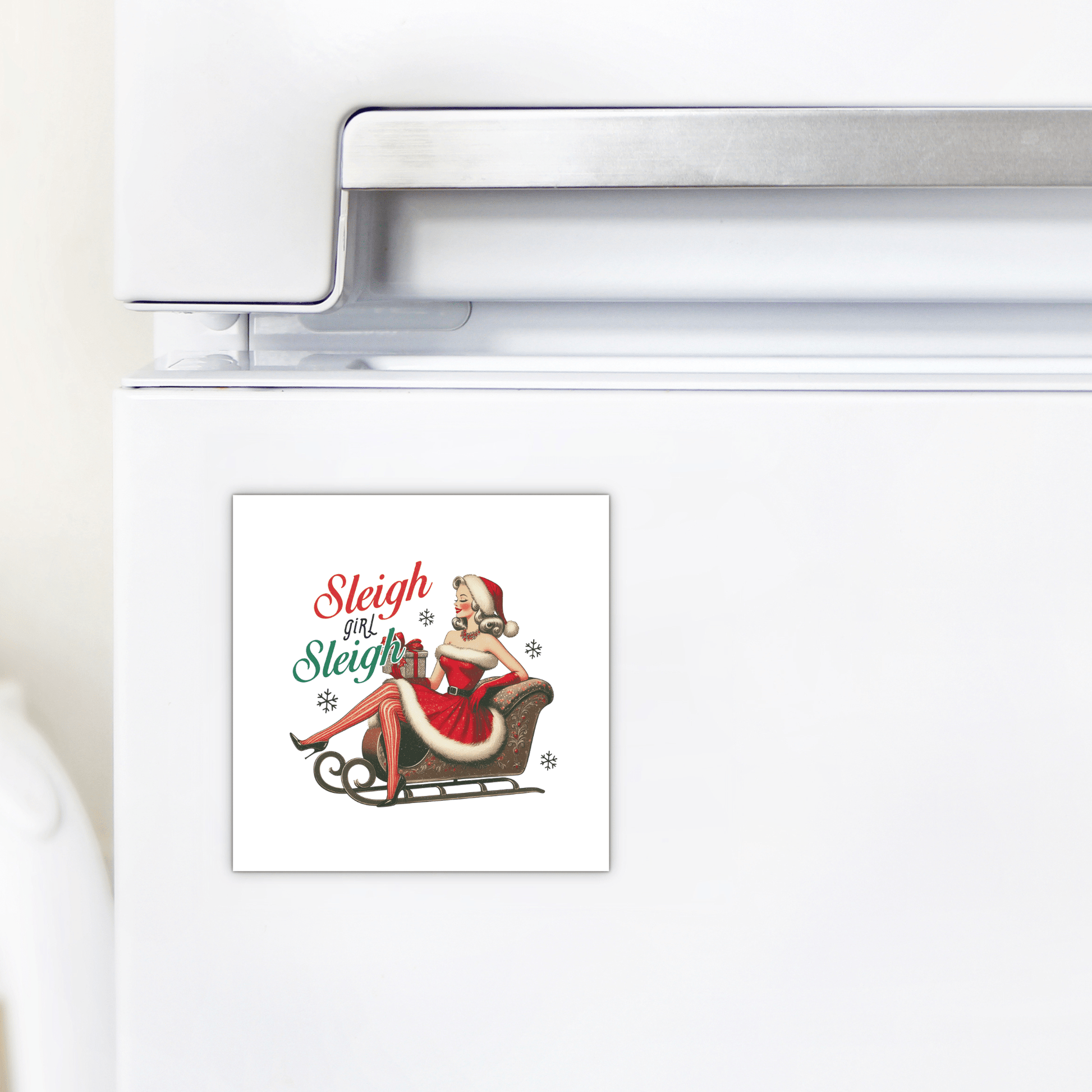 Add vintage flair to your kitchen with the Sleigh Girl Sleigh Magnet from Mirabilia Boutique—a retro holiday fridge magnet featuring a pin-up woman in a Santa outfit, gifts, and festive "Sleigh girl Sleigh" text in red and green.