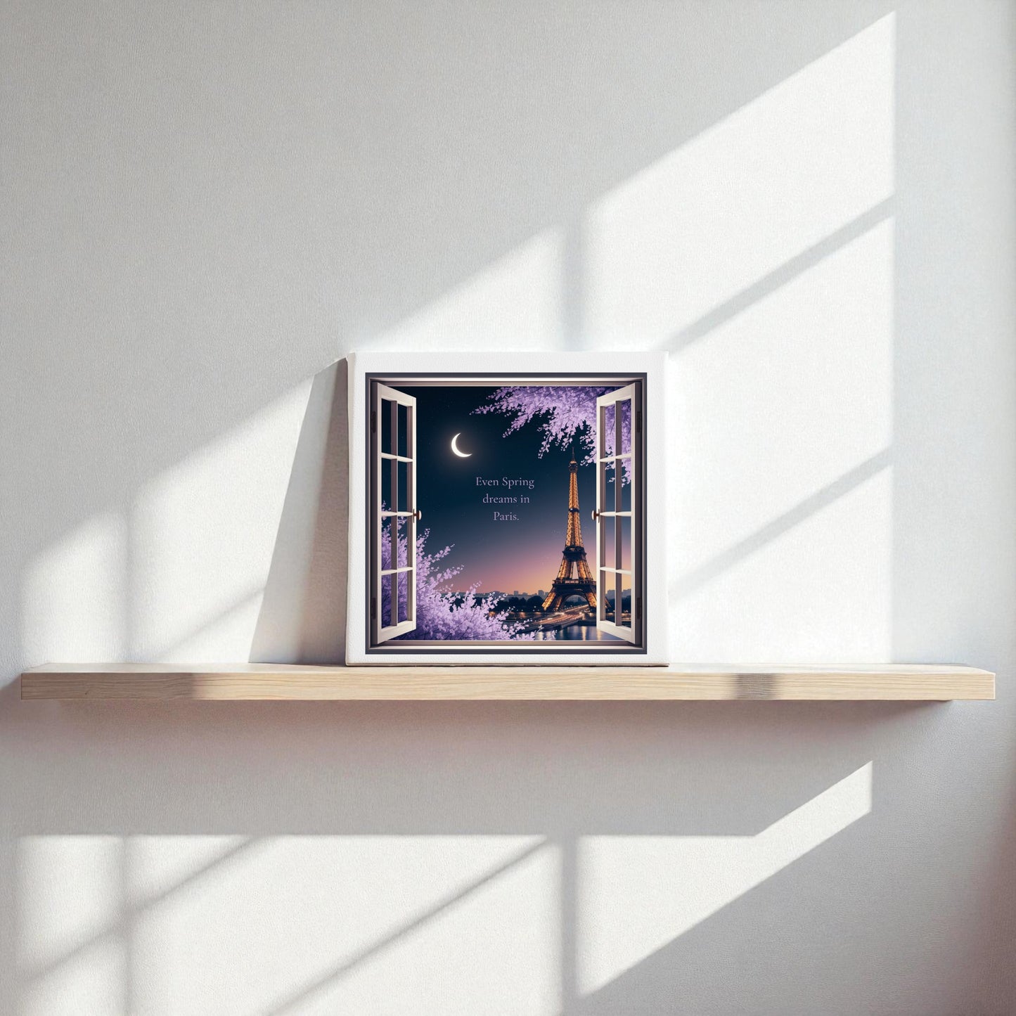 The Spring Dreams in Paris Canvas – Moonlit Eiffel Tower Art by Mirabilia Boutique features an 8x8 framed artwork on a minimalist wooden shelf, showing the Eiffel Tower at night with blossoming trees and a crescent moon.