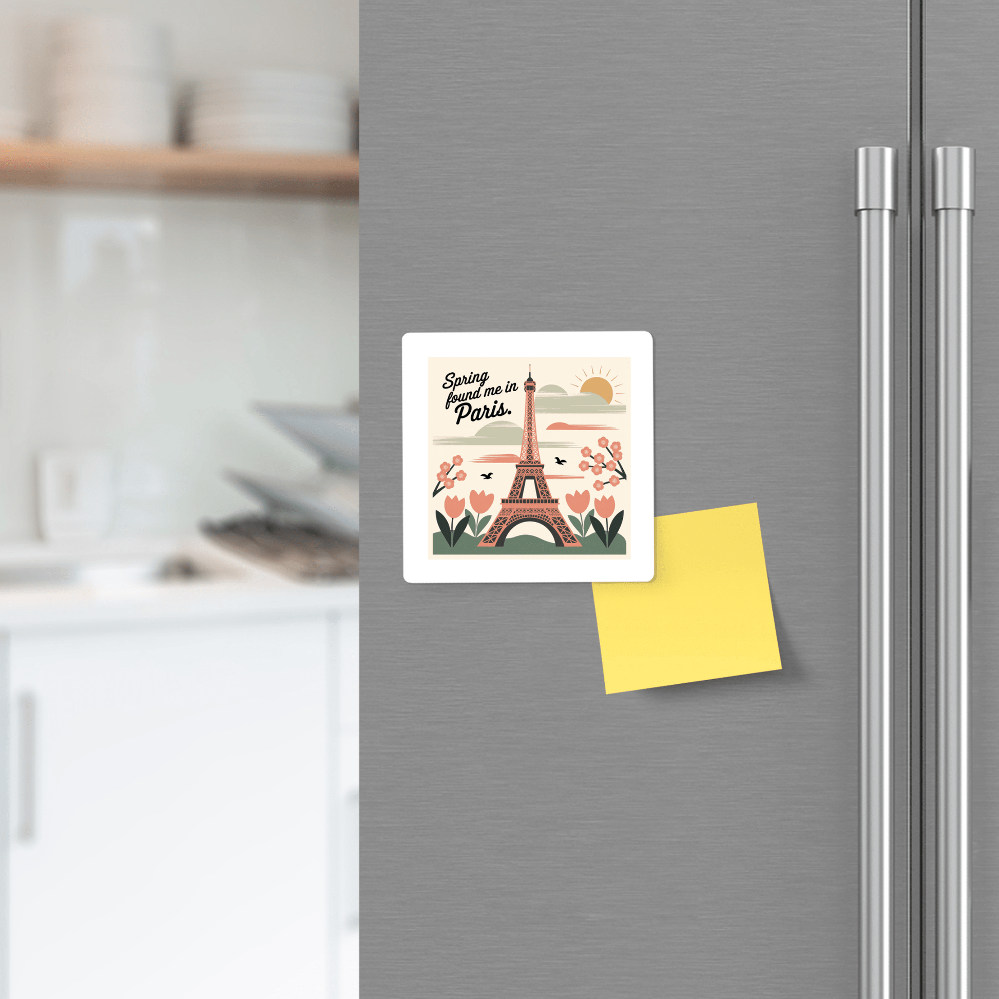 The Mirabilia Boutique "Spring Found Me in Paris Magnet – Eiffel Tower Charm" decorates a gray fridge door beside a blank yellow sticky note, adding a touch of spring and Parisian flair to the modern kitchen.