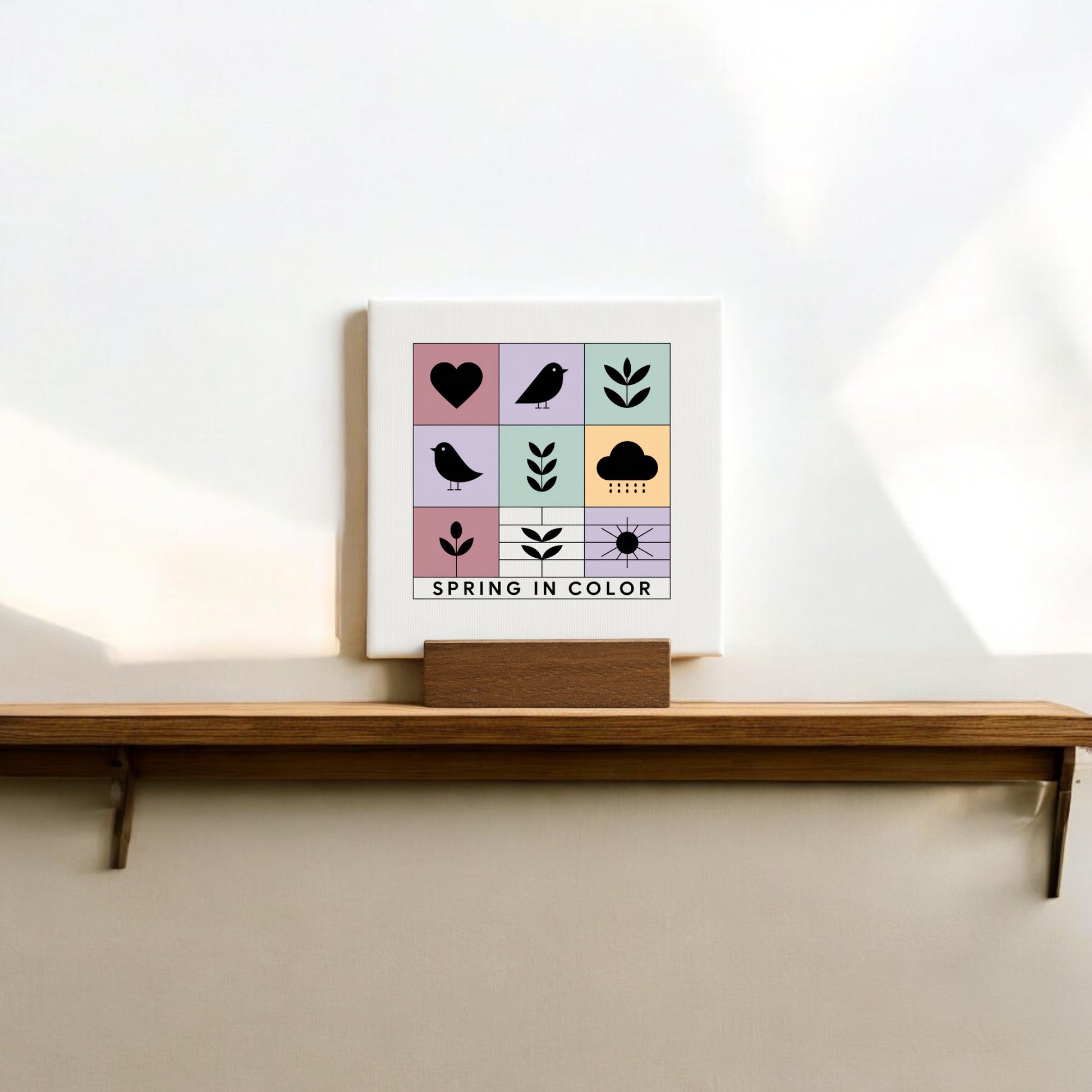 The Spring in Color Mini Canvas Sign with Wood Base by Mirabilia Boutique features cheerful spring icons and "SPRING IN COLOR" text—perfect décor to brighten your space.