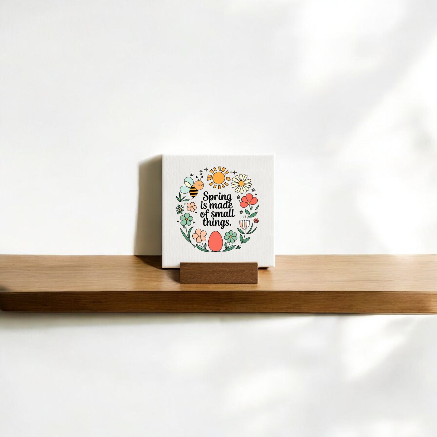 The Spring Is Made of Small Things Mini Canvas Sign by Mirabilia Boutique features a hand-drawn colorful flower wreath and the phrase "Spring is made of small things" on a white background—ideal for spring decor.