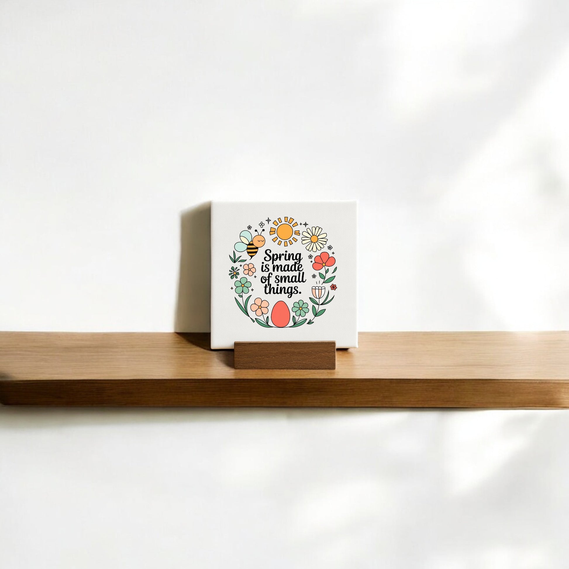 The Spring Is Made of Small Things Mini Canvas Sign by Mirabilia Boutique features a hand-drawn colorful flower wreath and the phrase "Spring is made of small things" on a white background—ideal for spring decor.
