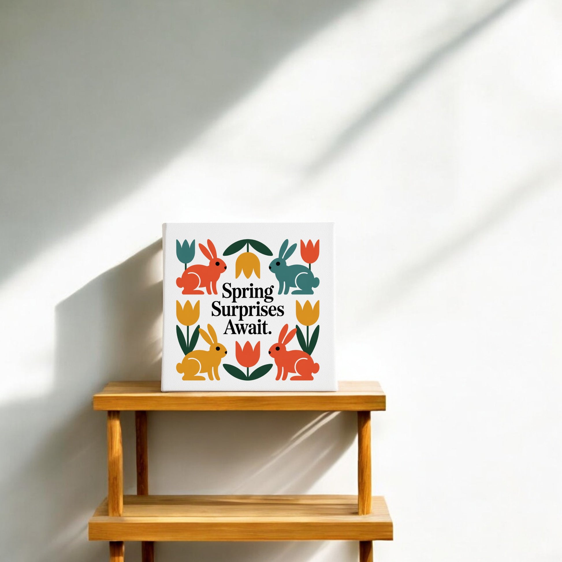 The Mirabilia Boutique "Spring Surprises Await Canvas – 8x8 Colorful Bunnies" adds cheerful Easter decor to a sunlit room, with its vibrant bunny and tulip design brightening a wooden shelf.