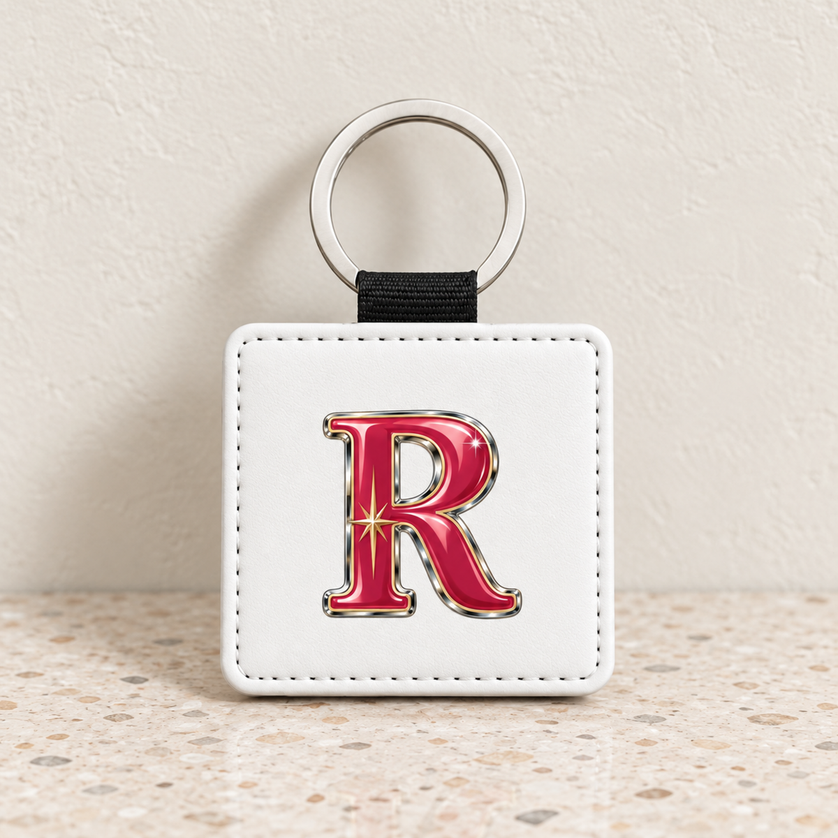 Square white stardust enamel Stardust Enamel Personalized Monogram Keychain featuring a large, metallic red letter R monogram with a star detail.