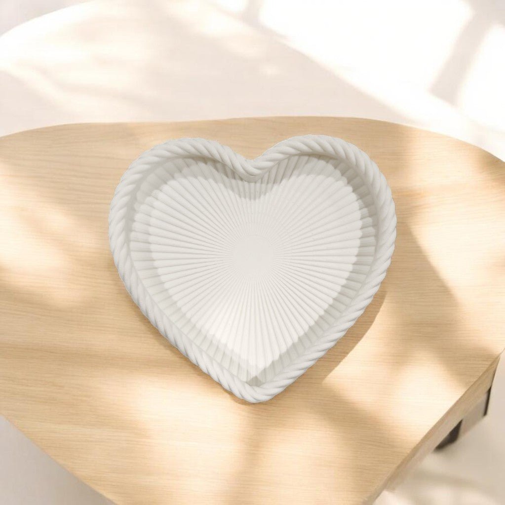 The Mirabilia Boutique Coastal Heart Tray in Matte White features a ribbed pattern and twisted border, adding subtle beach-inspired decor to your space with its elegant heart shape.
