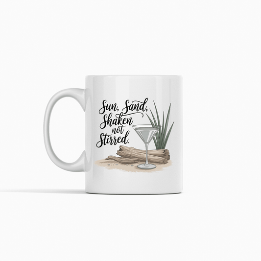 The Sun, Sand, Shaken Not Stirred Mug – Coastal Coffee Vibe by Mirabilia Boutique features driftwood, a green plant, sand, and a martini glass with the phrase “Sun, Sand, Shaken not Stirred.” Perfect for beach house decor. White background.