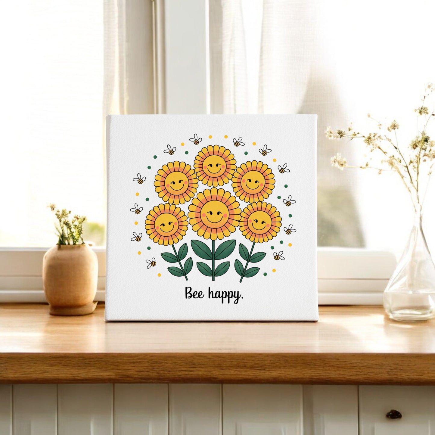 The Bee Happy Canvas – Smiling Sunflowers & Summer Joy by Mirabilia Boutique sits on a wooden table, surrounded by vases of flowers. Sheer curtains and sunlight in the background create a bright, cheerful home decor scene.