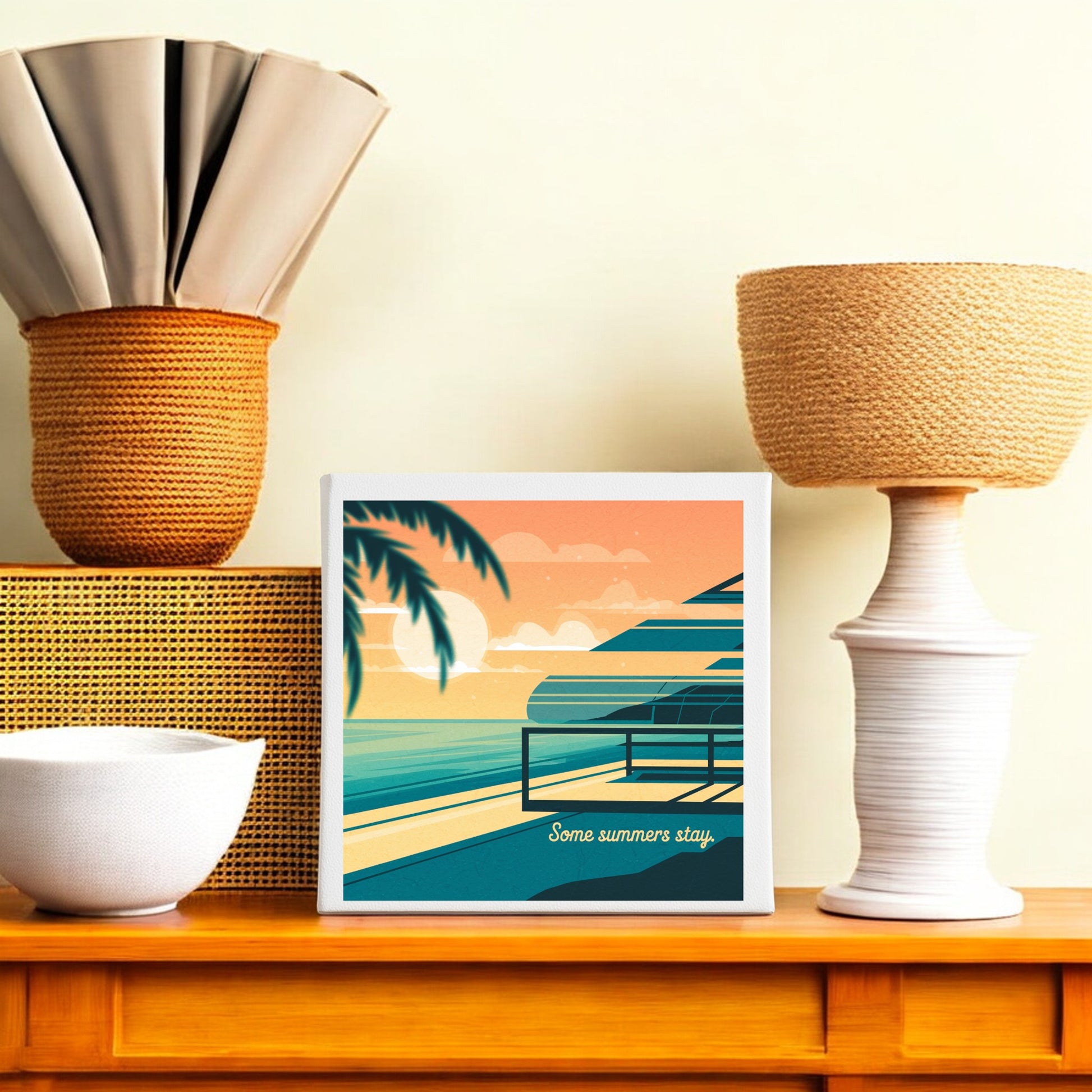 The "Some Summers Stay Canvas – Retro Coastal Sunset Art" by Mirabilia Boutique sits on a wooden shelf with neutral vases and baskets, making it the perfect coastal wall decor.