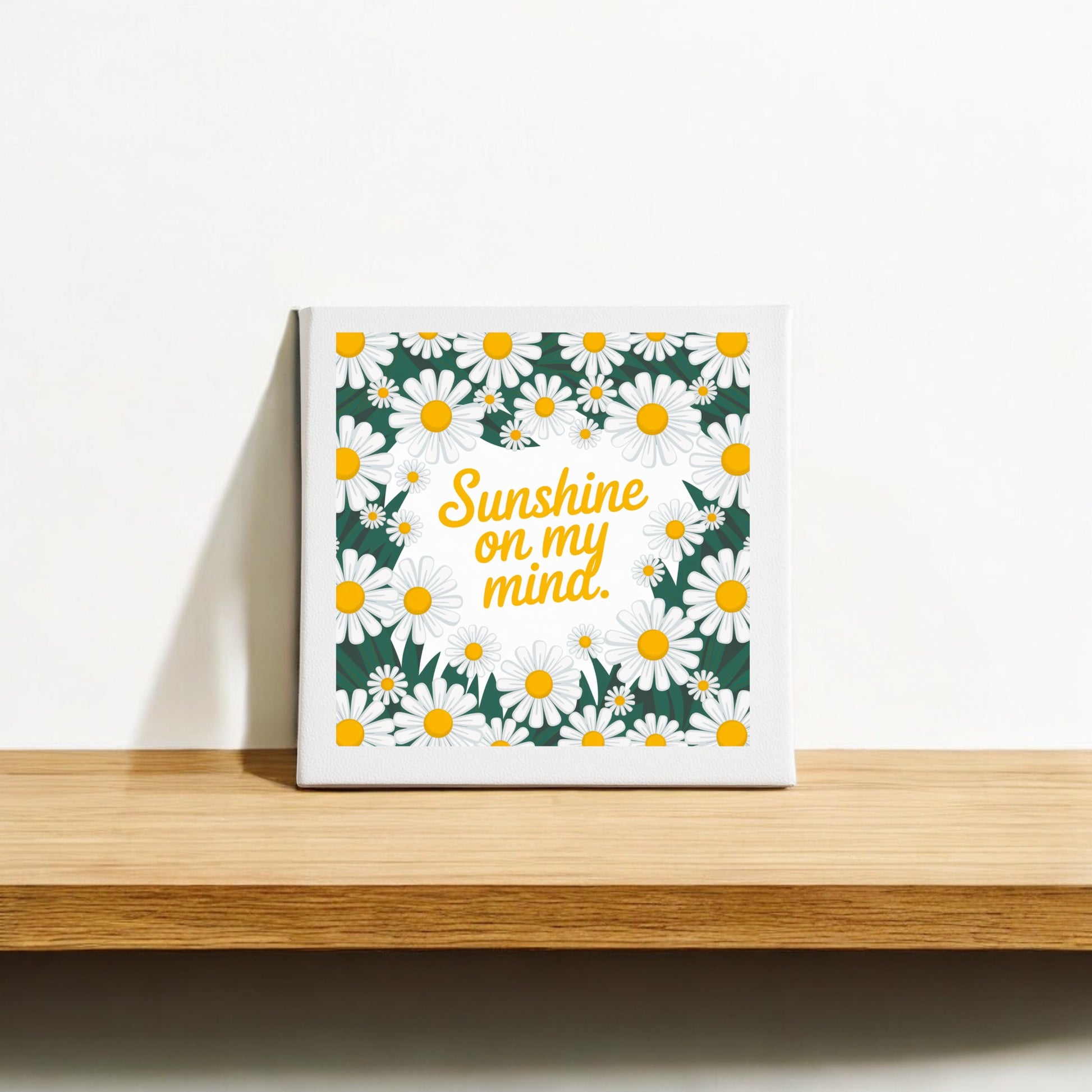 Mirabilia Boutique’s "Sunshine on My Mind Canvas – 8x8 Daisy Wall Art" features the phrase in yellow amid white and yellow daisies on a dark green background—perfect summer decor for any shelf or wall.