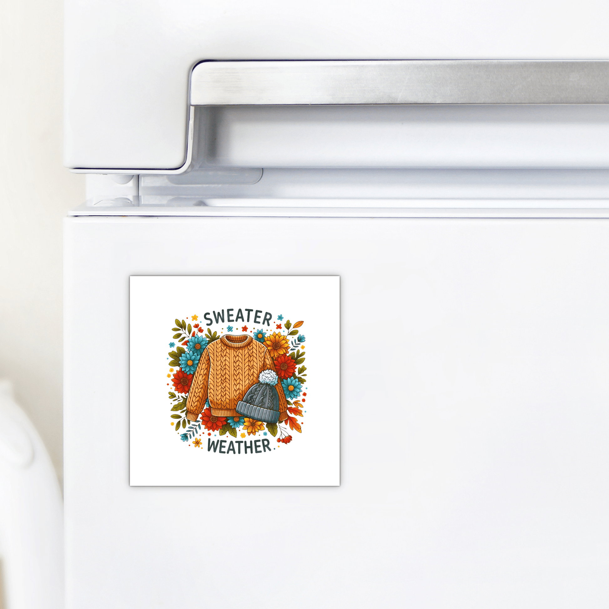 The Mirabilia Boutique Sweater Weather Magnet features autumn sweater art, a gray knit hat, leaves, and "Sweater Weather" text—perfect cozy fall fridge decor or a charming seasonal gift.