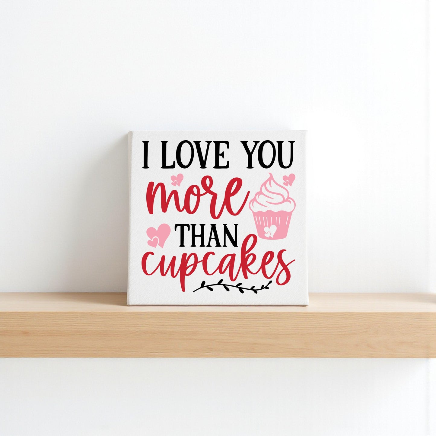 The Mirabilia Boutique “I Love You More Than Cupcakes” 8x8 canvas sign, adorned with pink hearts and sweet lettering, makes an adorable accent for kitchen wall art or Valentine’s Day home decor.
