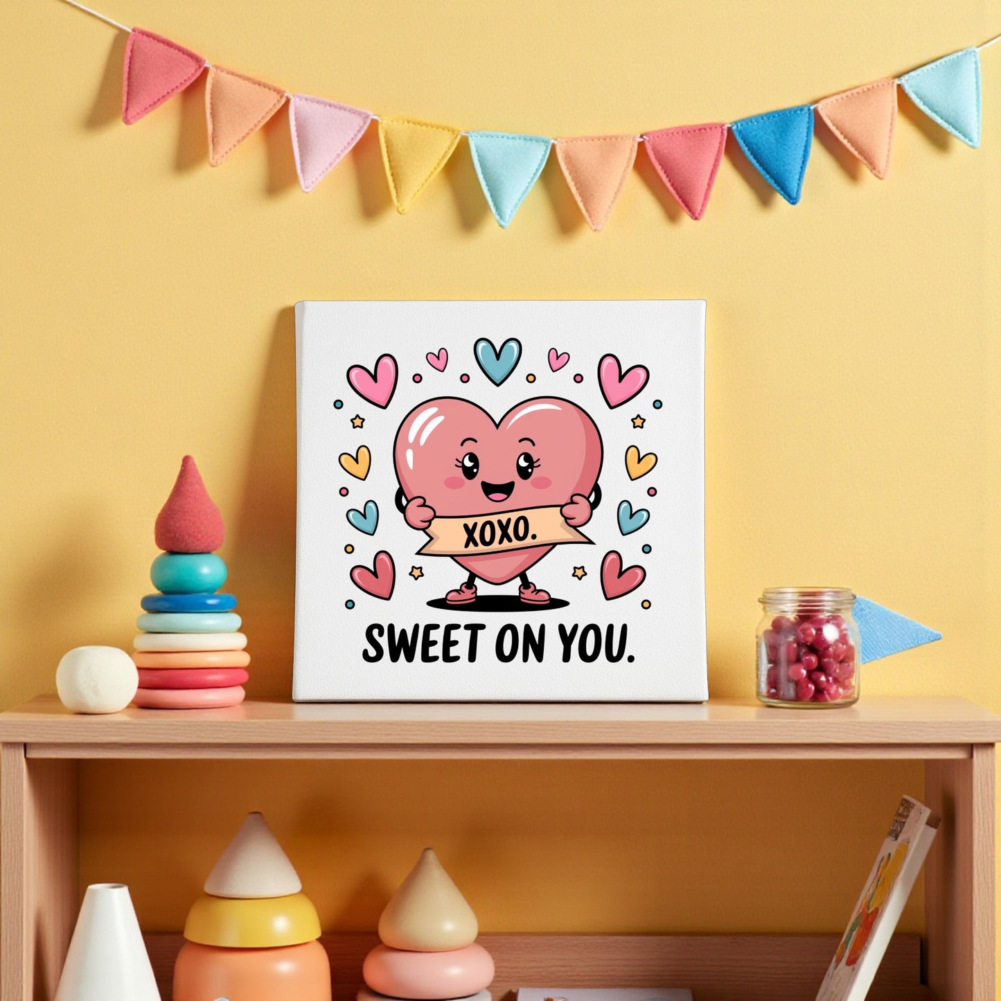 The Sweet On You XOXO Valentine Canvas by Mirabilia Boutique features a framed cartoon heart with "XOXO," colorful hearts, and "SWEET ON YOU" text—ideal for nursery wall art or Valentine's decor. Pastel garland, toys, and candy jars accent the scene.