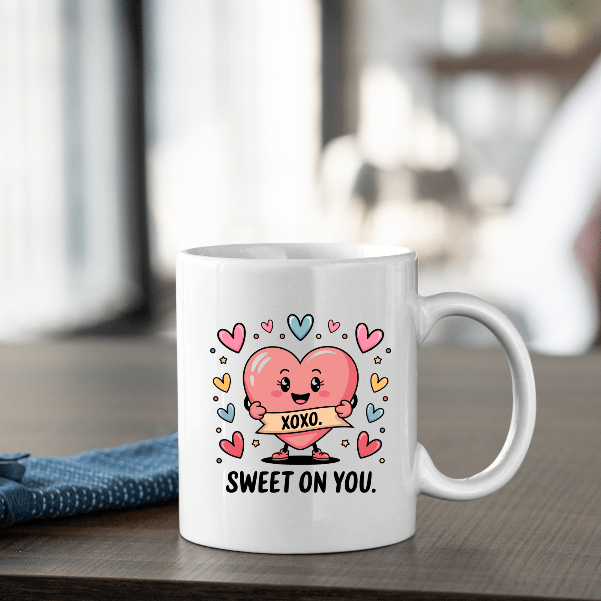 Brighten your space with the Sweet On You Heart Mug by Mirabilia Boutique—a white mug featuring a pink cartoon heart with an "XOXO" sign, colorful hearts, and "SWEET ON YOU." A charming Valentine's gift for someone special!.
