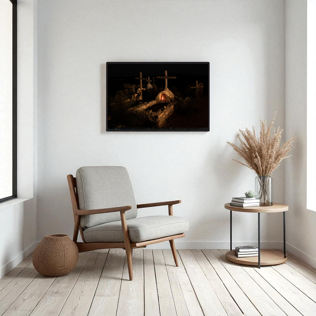A cozy modern living room featuring a light armchair, a round side table with dried grass decor, and the “Terlingua Cemetery at Night” framed fine art print by Mirabilia Boutique displayed on the wall—this striking artwork showcases West Texas photography with a dark, moody graveyard scene inspired by the historic Terlingua Cemetery, complete with crosses and warm lighting.