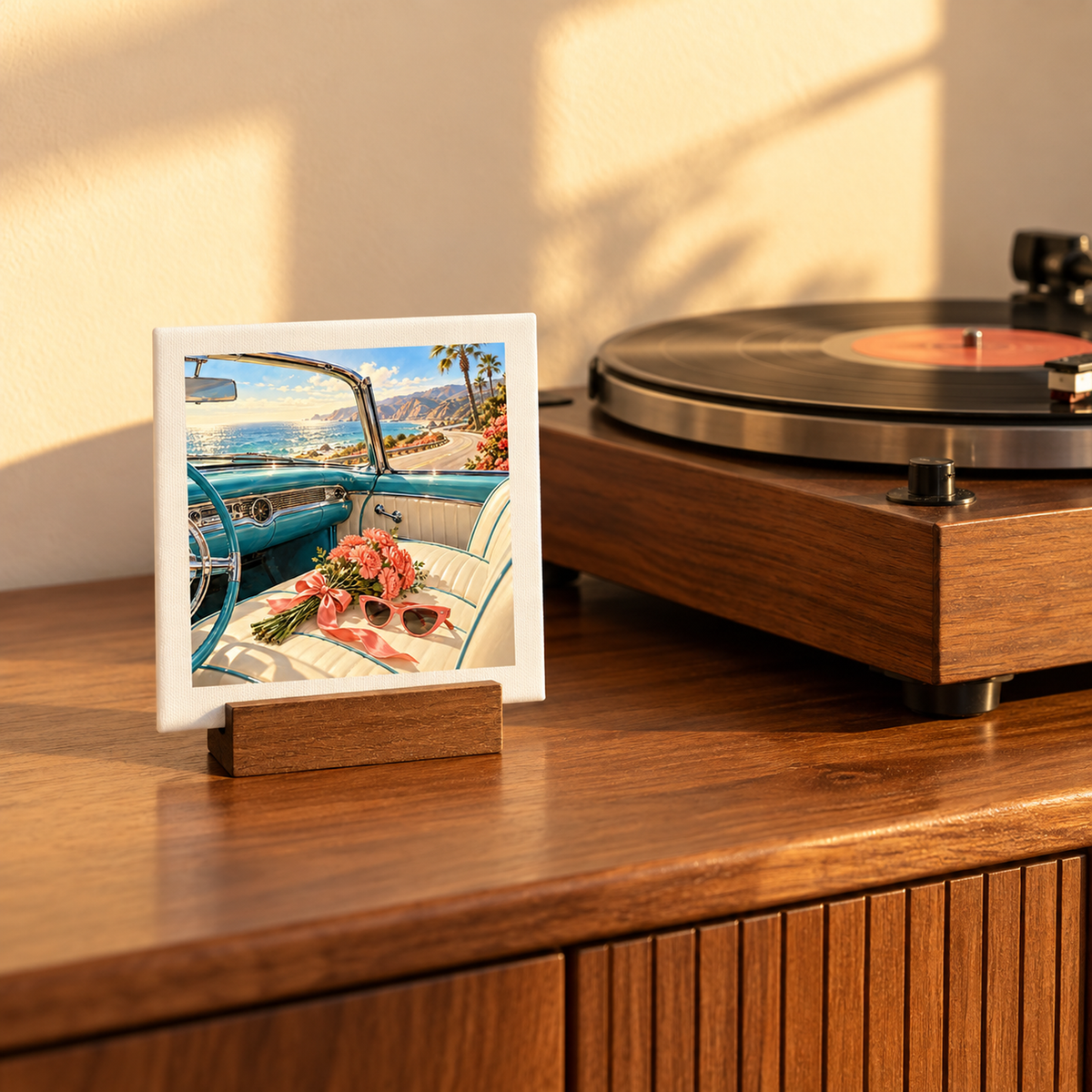 The Best Is Still Ahead Birthday Mini Sign, a square canvas print on a wooden stand, depicts the interior of a vintage blue convertible parked by the coast next to a record player on a wooden cabinet, serving as charming mid-century decor.