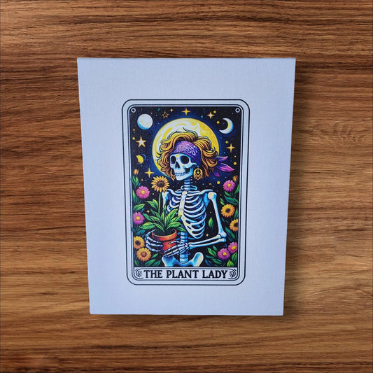 The "The Plant Lady Gardening" 8x10 Canvas Sign by Mirabilia Boutique features a whimsical skeleton with a floral bandana, holding a potted plant amidst vibrant flowers, stars, and a crescent moon. Framed like a tarot card, this rectangular canvas is perfect for tarot lovers and adds charm to any space.