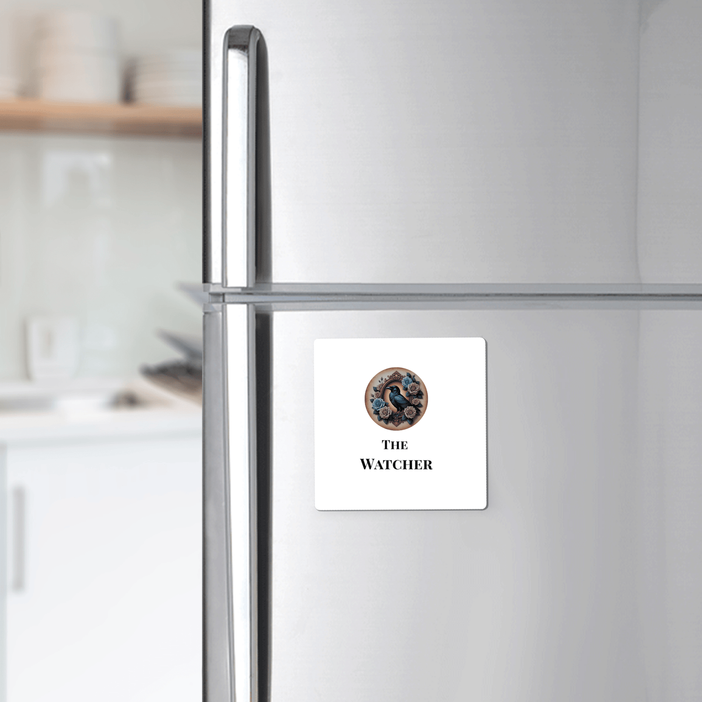 A silver fridge displays Mirabilia Boutique’s "The Watcher Magnet"—a square white magnet with googly eyes and gothic text, perfect for dark academia fans. Kitchen shelves and dishes complete the Dead Regency aesthetic.