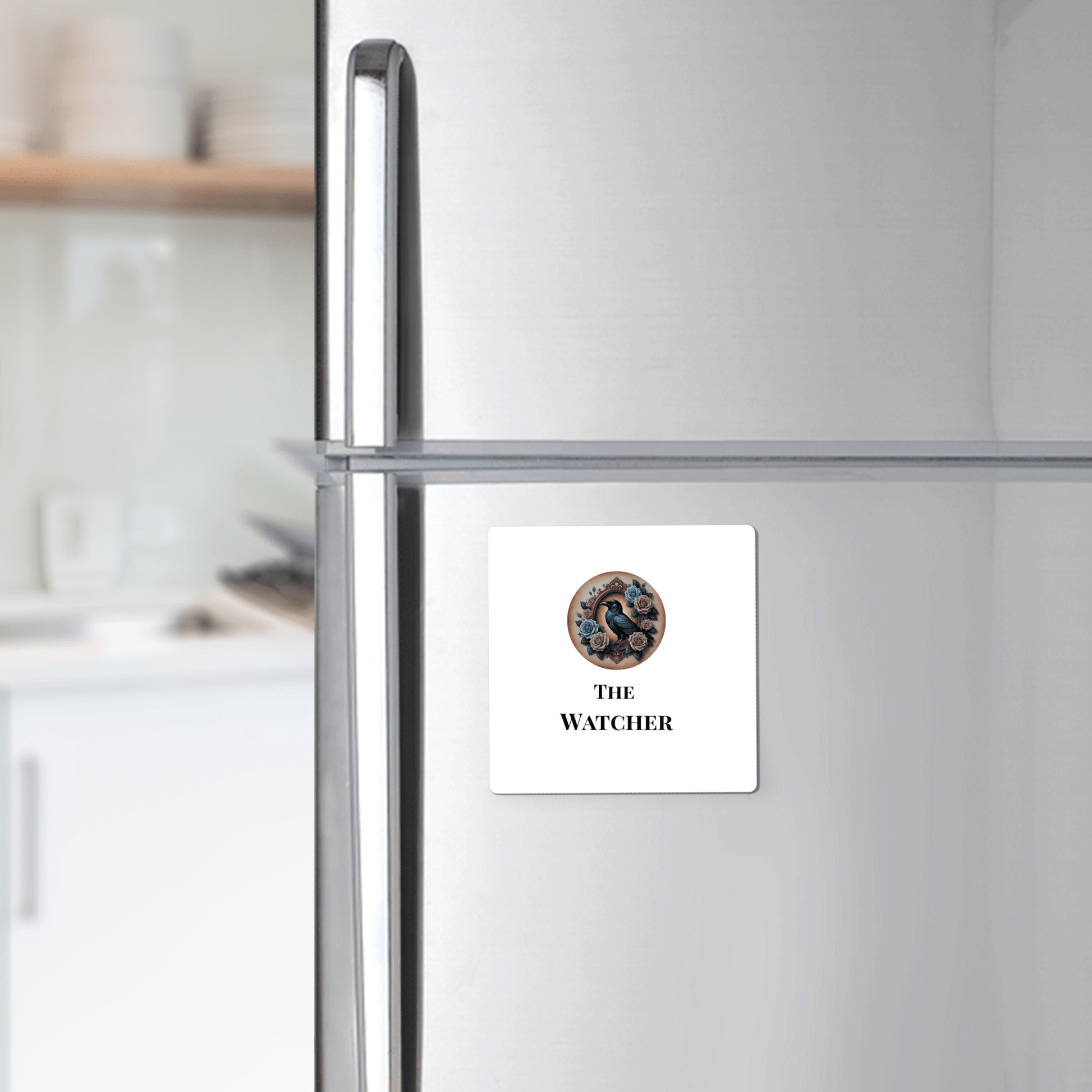 A silver fridge displays Mirabilia Boutique’s "The Watcher Magnet"—a square white magnet with googly eyes and gothic text, perfect for dark academia fans. Kitchen shelves and dishes complete the Dead Regency aesthetic.