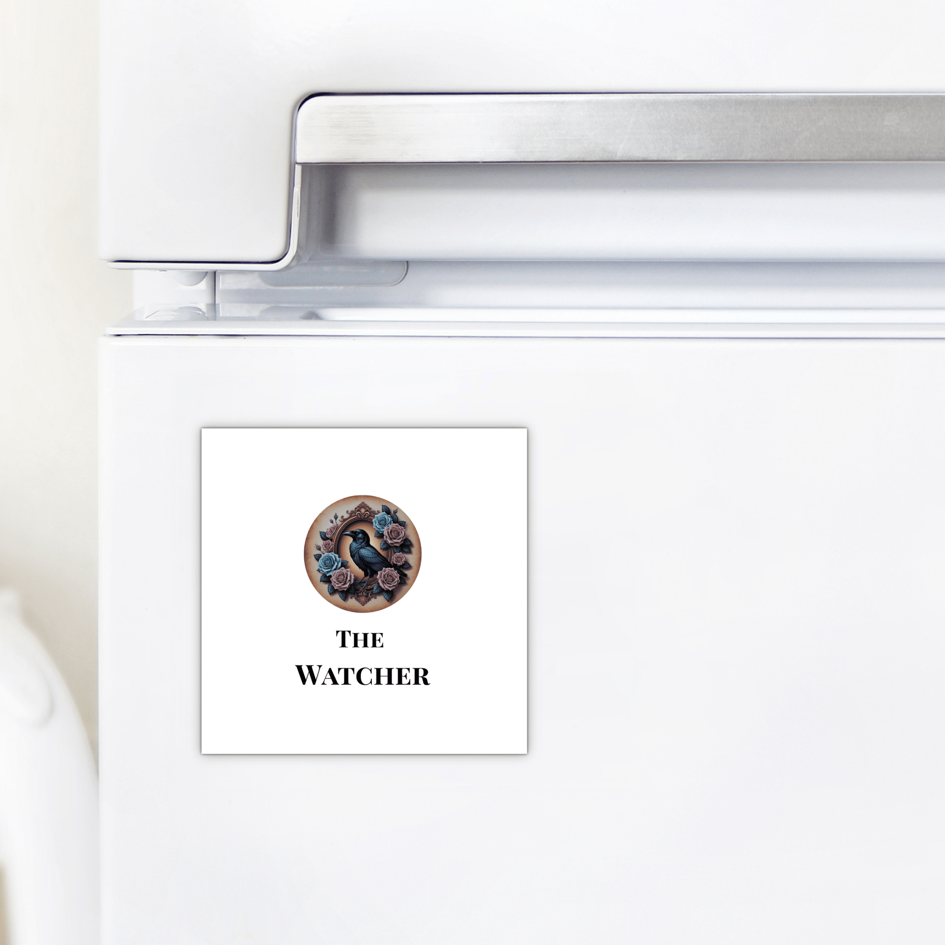 A square "The Watcher Magnet" by Mirabilia Boutique features a black bird and flowers above “THE WATCHER”—a gothic fridge accessory and perfect dark academia gift for home decor fans.