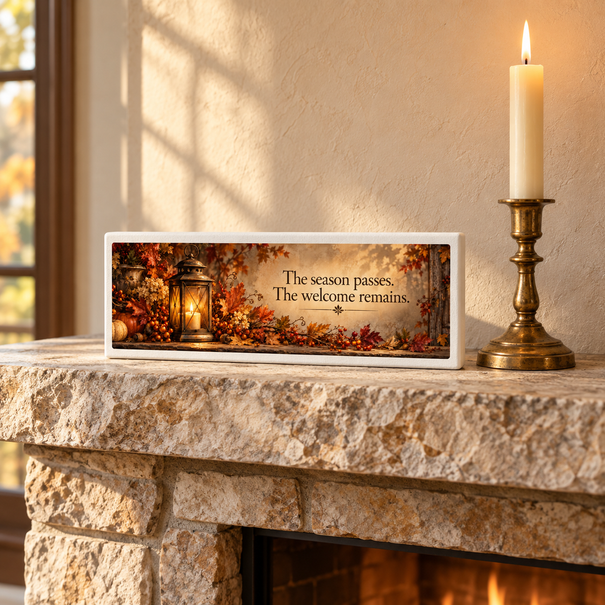 A stone fireplace displays a lit candle, lantern decor, and the Mirabilia Boutique The Welcome Remains Autumn Shelf Sitter with autumn leaves. Sunlight pours through a nearby window.