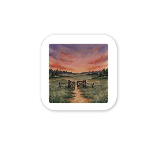 A dirt path winds through tall grass toward a wooden fence and gate, framed by distant trees beneath a vivid, dramatic sunset—an inspiring and tranquil scene beautifully depicted in the Mirabilia Boutique “There Is More Sunset Landscape Magnet | Inspirational Art.”.