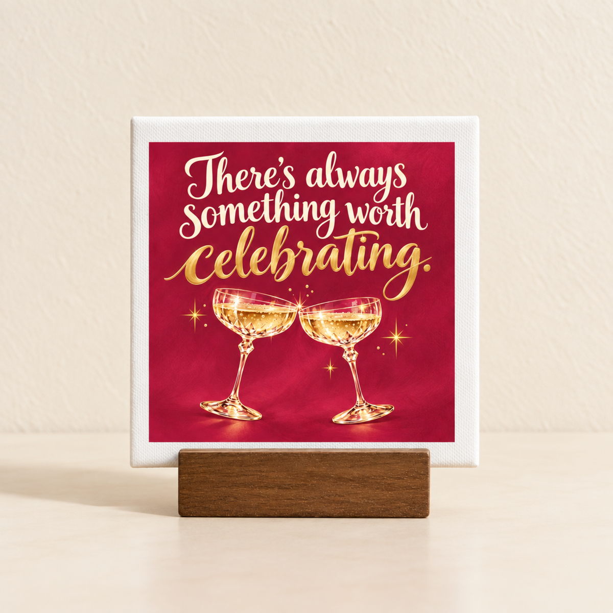 A square There’s Always Something Worth Celebrating Mini Bar Sign on a wooden stand, featuring the text “There’s always something worth celebrating” above two clinking champagne glasses on a red background.