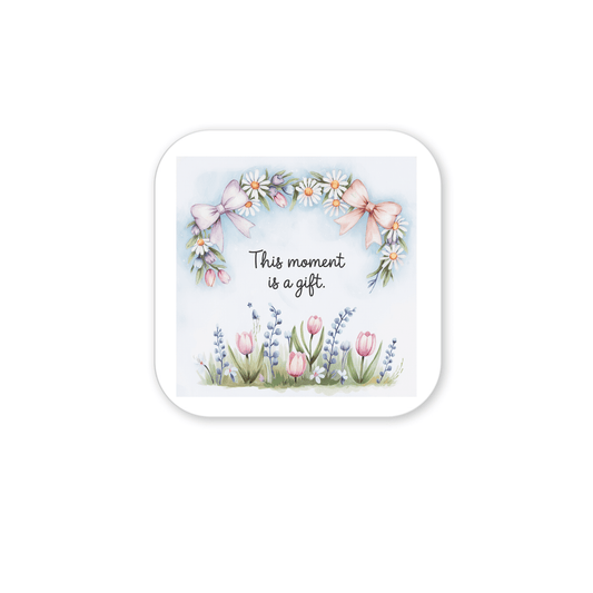 The "This Moment Is a Gift Magnet – Floral Spring Quote" by Mirabilia Boutique features pink bows, daisies, and tulips with the message "This moment is a gift." Its soft pastel design makes it an uplifting, inspirational gift.