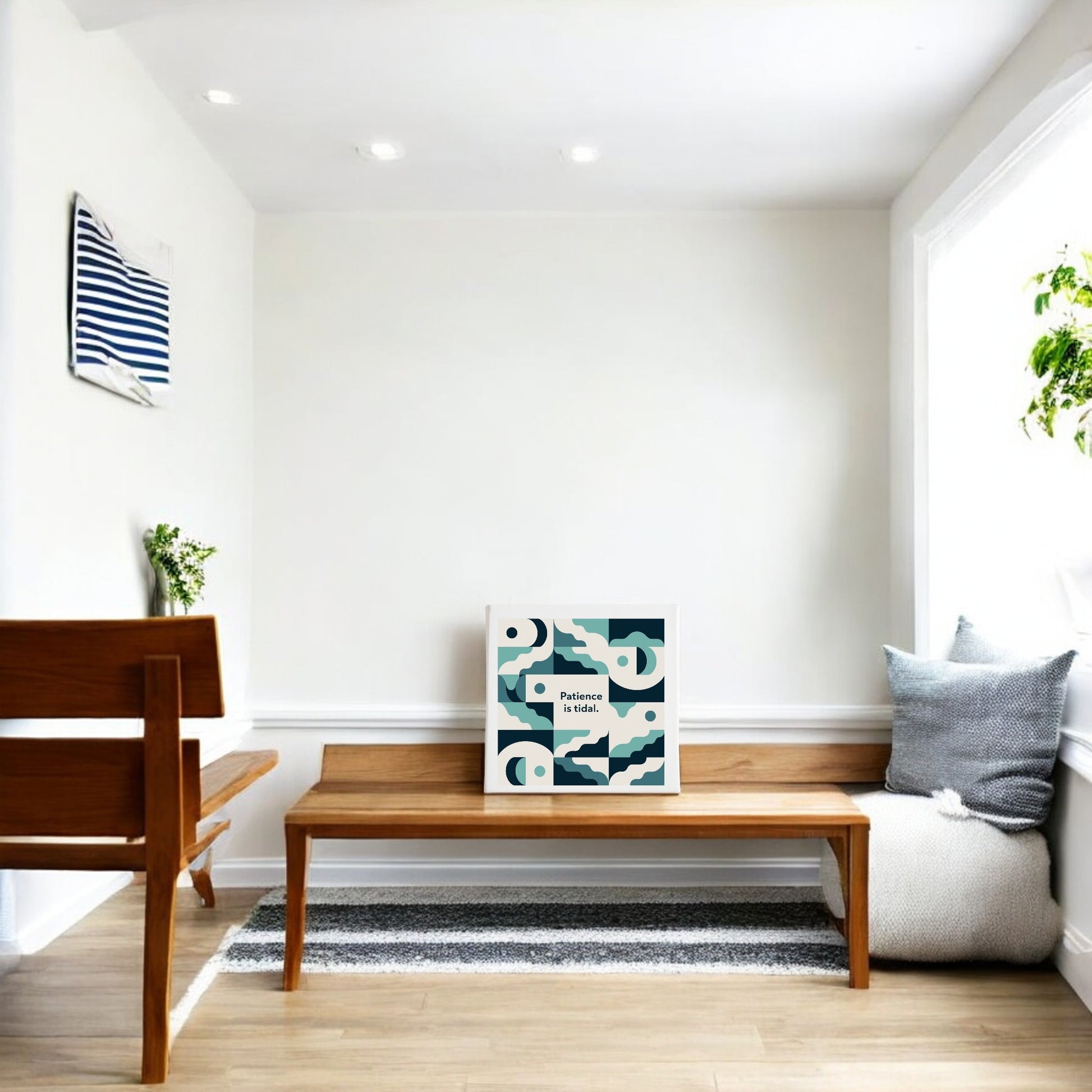 A minimalist room with white walls, a wooden bench, small table, and gray pillow is enhanced by the "Patience Is Tidal Canvas – Calm Coastal Wall Art" from Mirabilia Boutique, adding a serene coastal touch to the tranquil space.