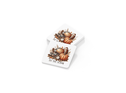 The Tis’ the Season Coaster Set by Mirabilia Boutique includes two square coasters with football and pumpkin fall designs—ideal autumn decor or a thoughtful game day gift.