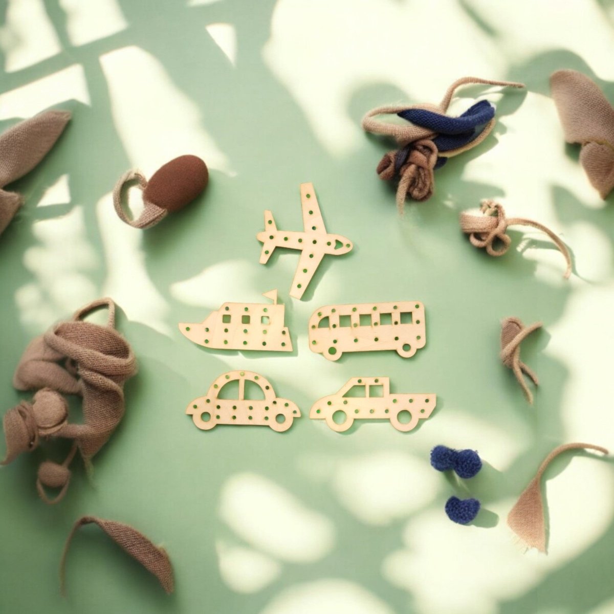 Mirabilia Boutique’s Transportation Vehicle Lacing Trays for Kids—featuring a plane, boat, bus, car, and jeep—sit on a pale green surface. Ideal for preschoolers to learn and develop fine motor skills as light and shadow play around them.