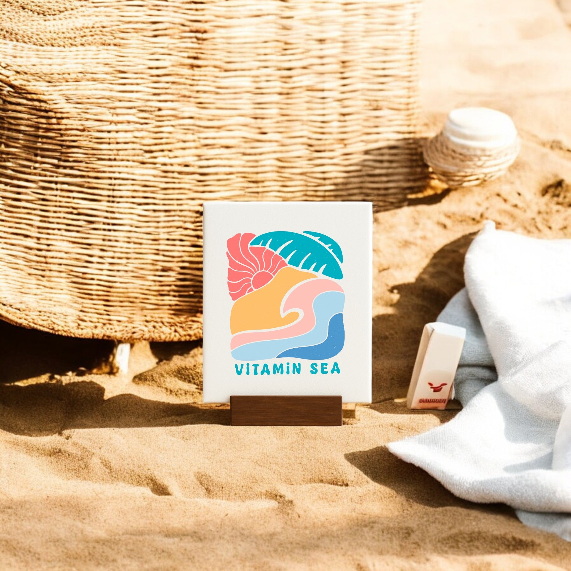 The Mirabilia Boutique Vitamin Sea Mini Canvas Sign (4x6) features beachy graphics and adds a splash of coastal decor to your space—perfect next to a wicker basket, white towel, and sunscreen for a relaxing vibe.